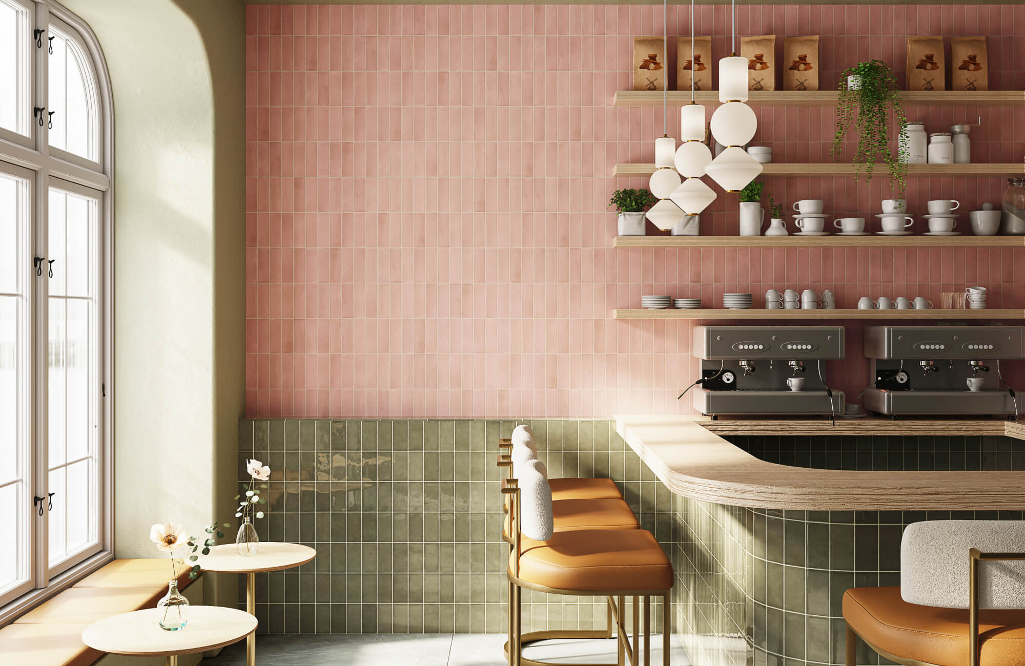 Stylish café interior with pink and green zellige-style tile walls, curved bar counter, espresso machines, sculptural pendant lights, and cozy seating by a window.