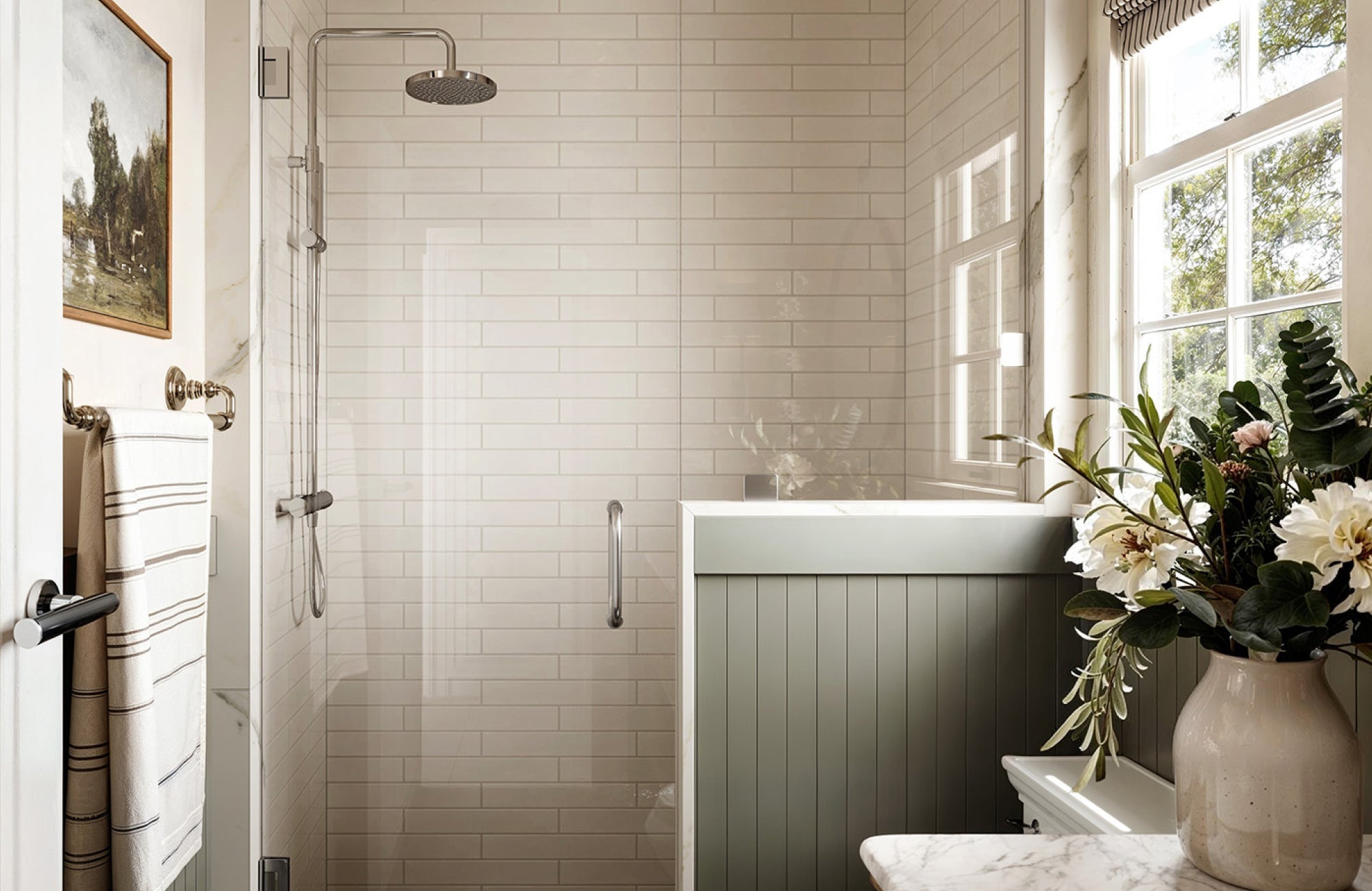 Walk-in shower with glossy white subway tiles and chrome fixtures beside a green half-wall panel.