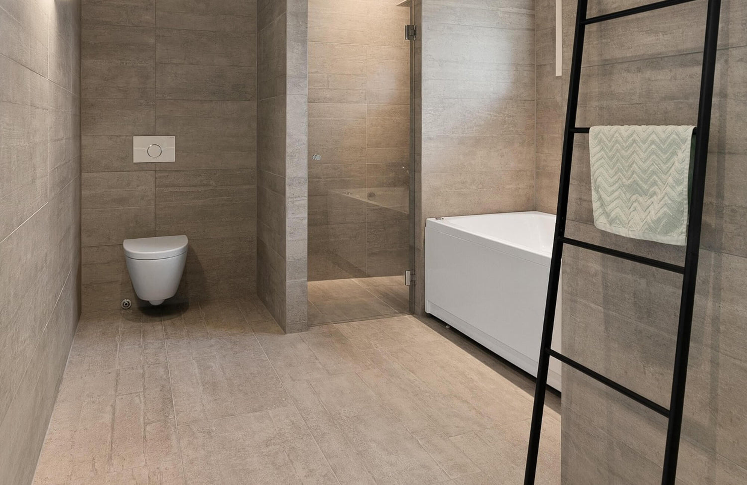 Contemporary bathroom showcasing neutral-toned bathroom tile with a stone-like texture, seamlessly covering the walls and floor to create a cohesive, minimalist look complemented by a glass shower and sleek fixtures.