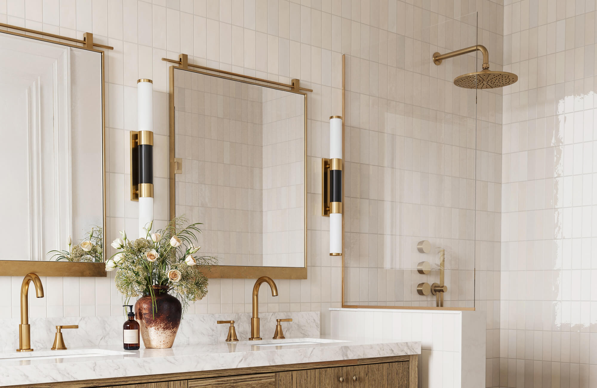 Elegant bathroom with symmetrical mirror placement above double vanity, featuring brass frames, sconces, and marble countertop.