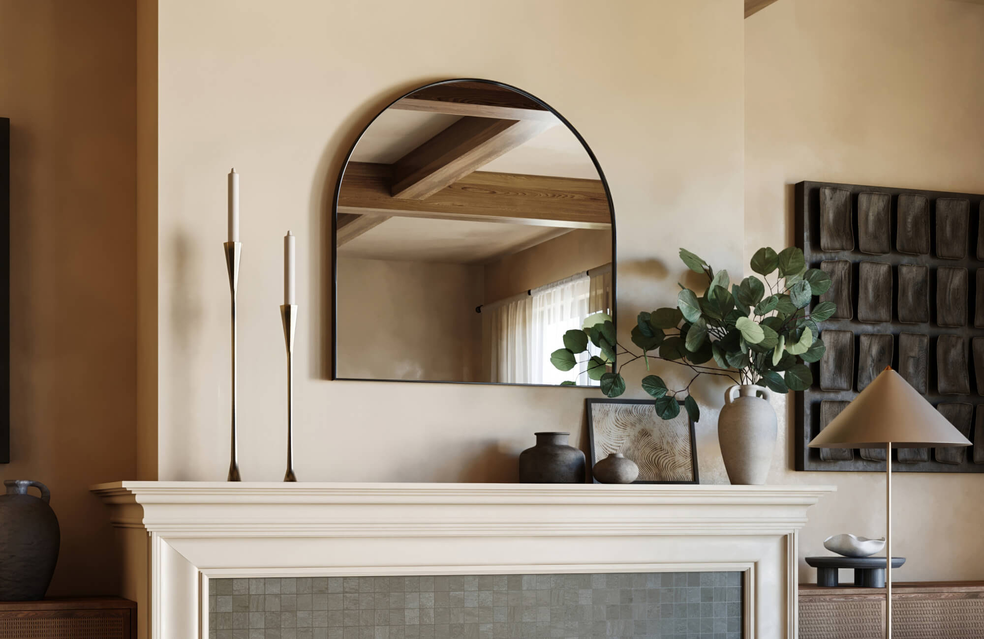Neutral-toned living space with arched wall mirror above fireplace mantel, styled with sculptural vases, taper candles, and modern greenery