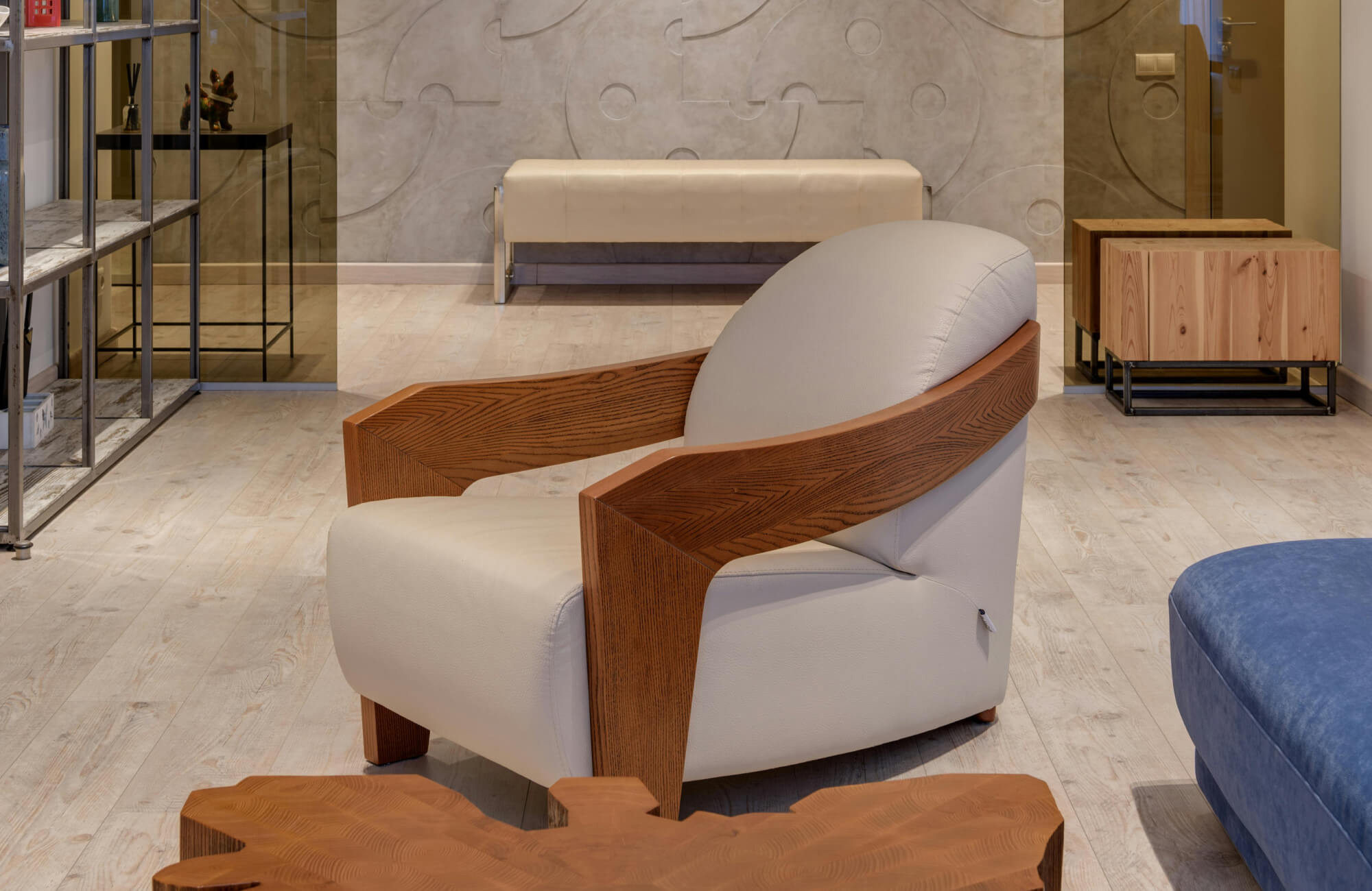 Modern armchair with light beige upholstery and rich wooden armrests, set on a beige wood look floor in a stylish interior.