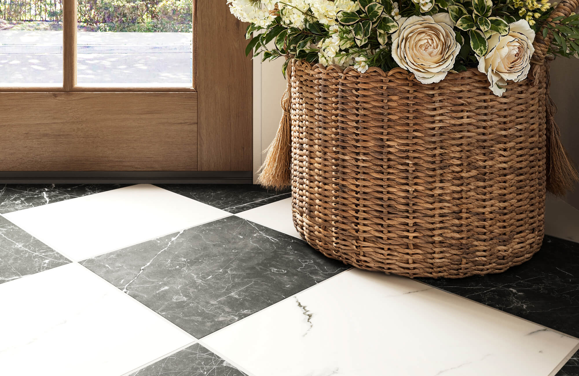 Classic black and white marble checkerboard tiles add timeless elegance to an entryway, complementing a woven basket filled with fresh flowers.