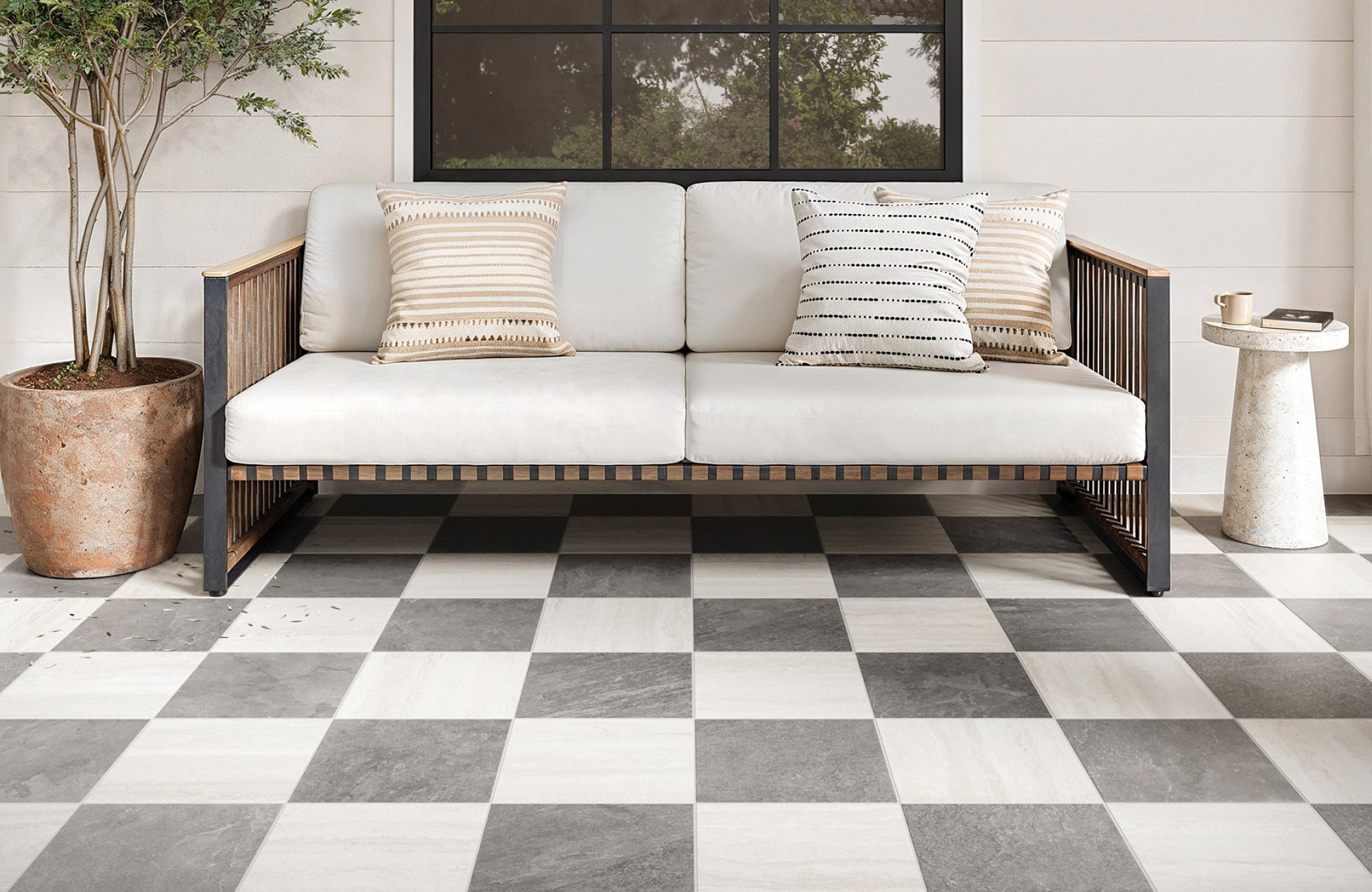 Outdoor patio with checkerboard tile in grey and white, paired with modern wood seating.