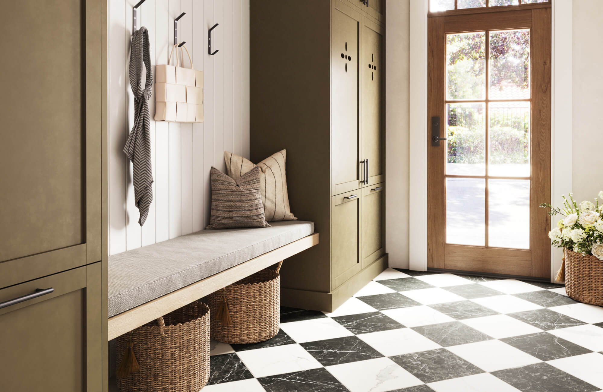 Stylish mudroom with black and white checkered tiles, olive cabinetry, a cozy bench with pillows, woven baskets, and a natural wood door.