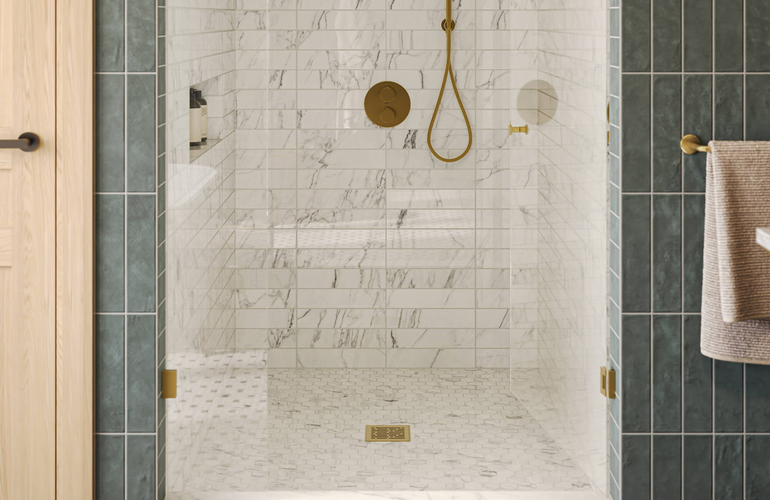 Walk-in shower with white marble look subway tile, hex mosaic floor, and brushed brass fixtures framed by deep green tiles.