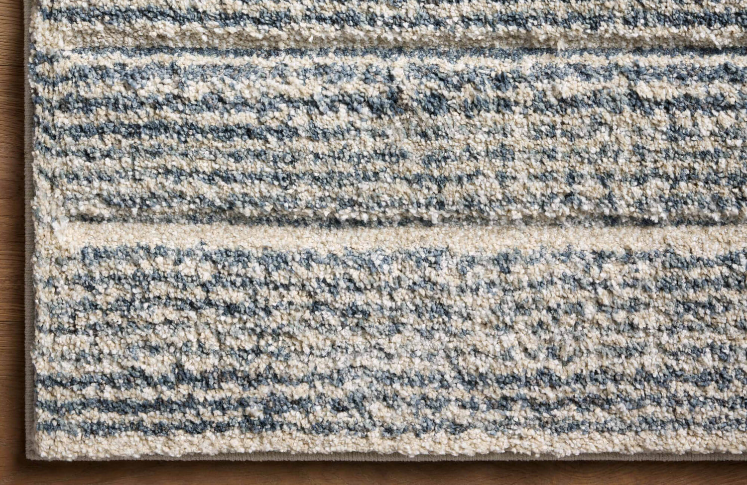A low-pile polypropylene rug with textured linear patterns in soft neutral and blue tones, adding depth and warmth to any space.