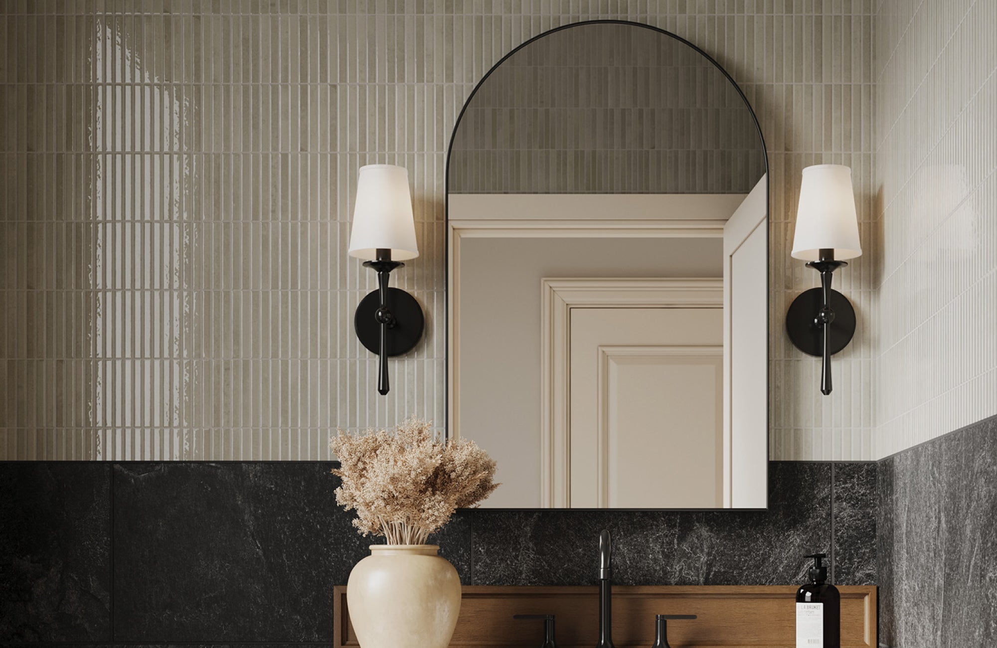 Elegant black wall sconces with white shades add symmetry and warmth to a modern bathroom vanity with tiled walls.