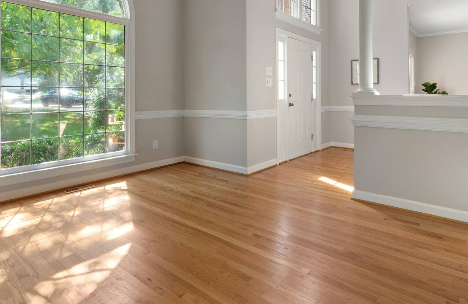 Bright living room with large windows and wood look flooring, showcasing timeless home design and resale appeal.