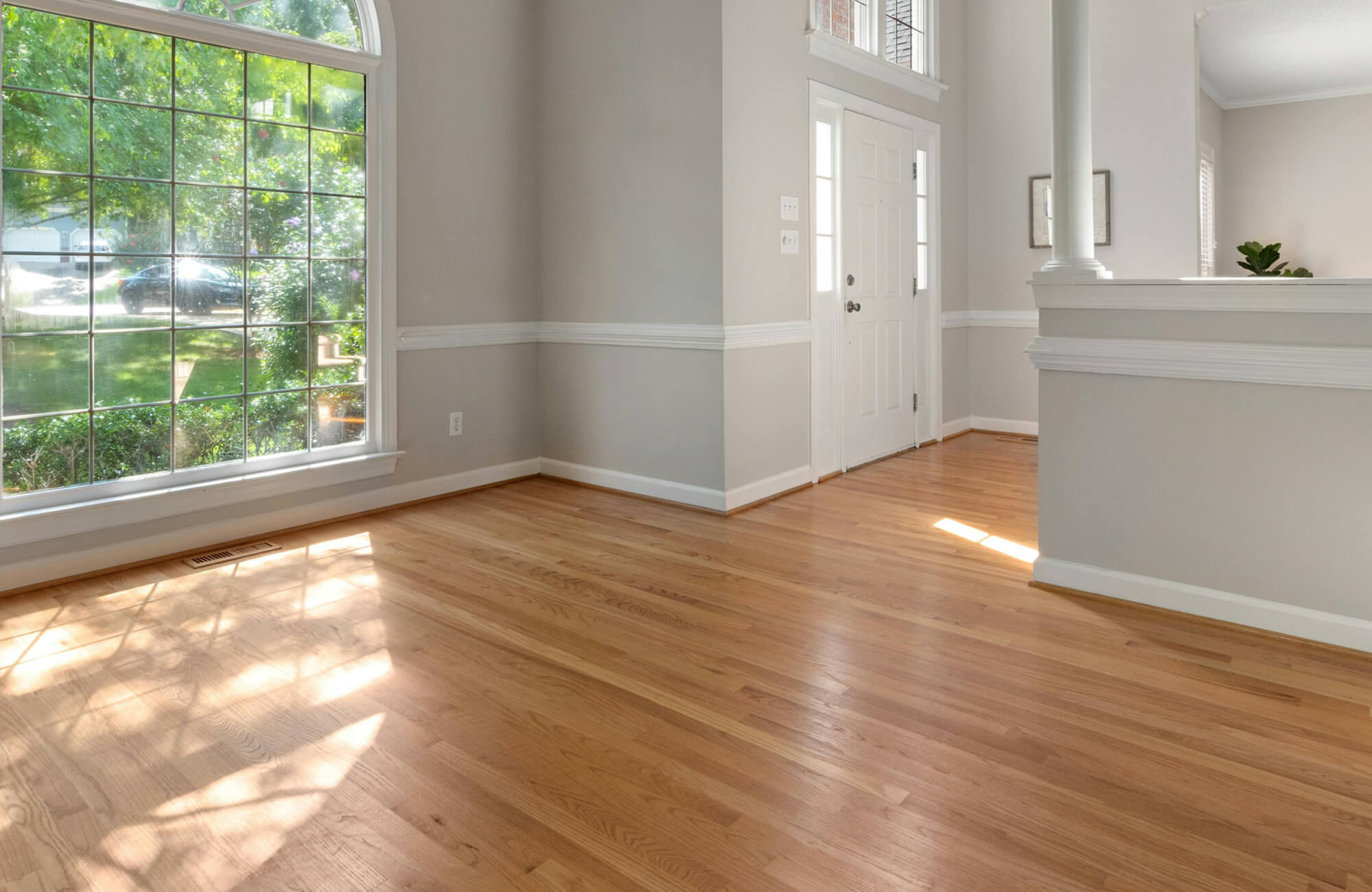 Bright living room with large windows and wood look flooring, showcasing timeless home design and resale appeal.
