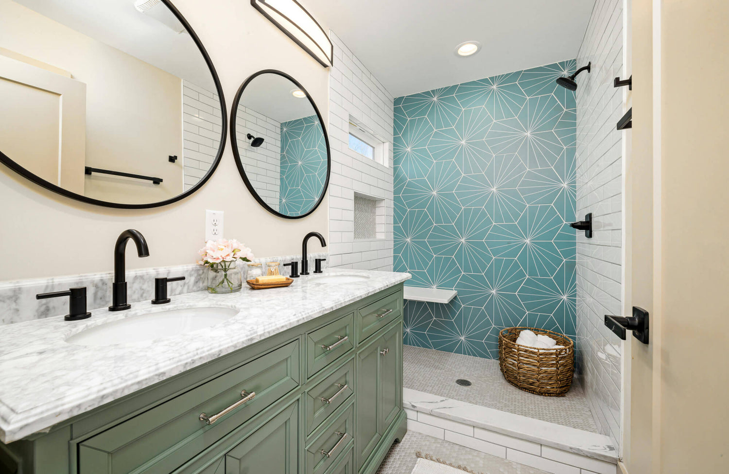 Modern bathroom featuring a double vanity with sage green cabinetry, marble countertop, and matte black fixtures, complemented by geometric teal shower tiles that add a refreshing, contemporary flair.