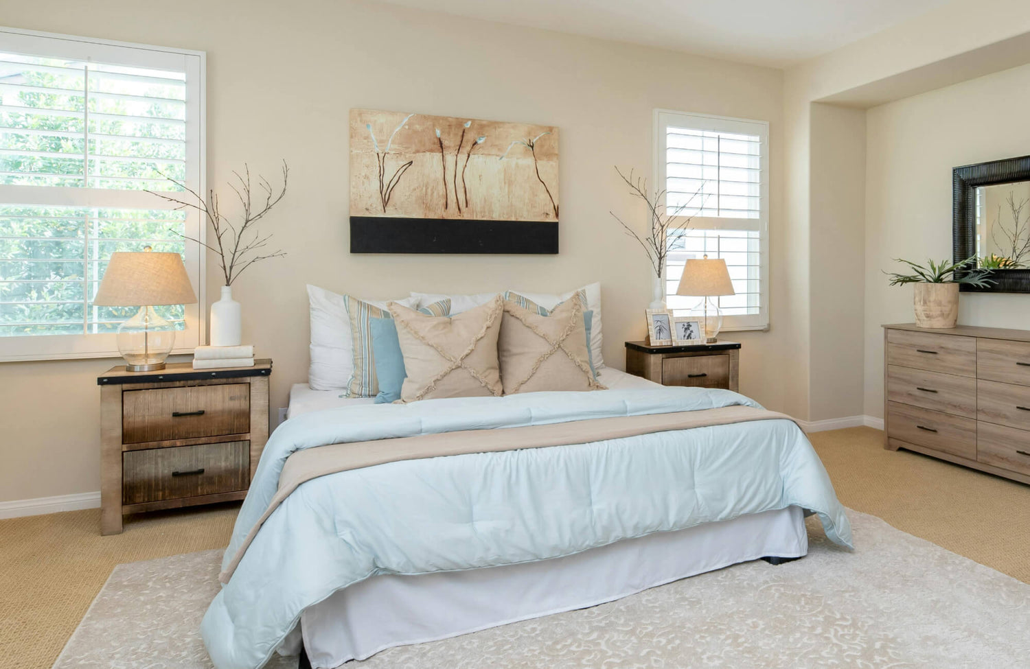 Bright bedroom with a soft patterned rug underfoot, styled with rustic wood nightstands topped with glass-base table lamps that provide warm ambient lighting.