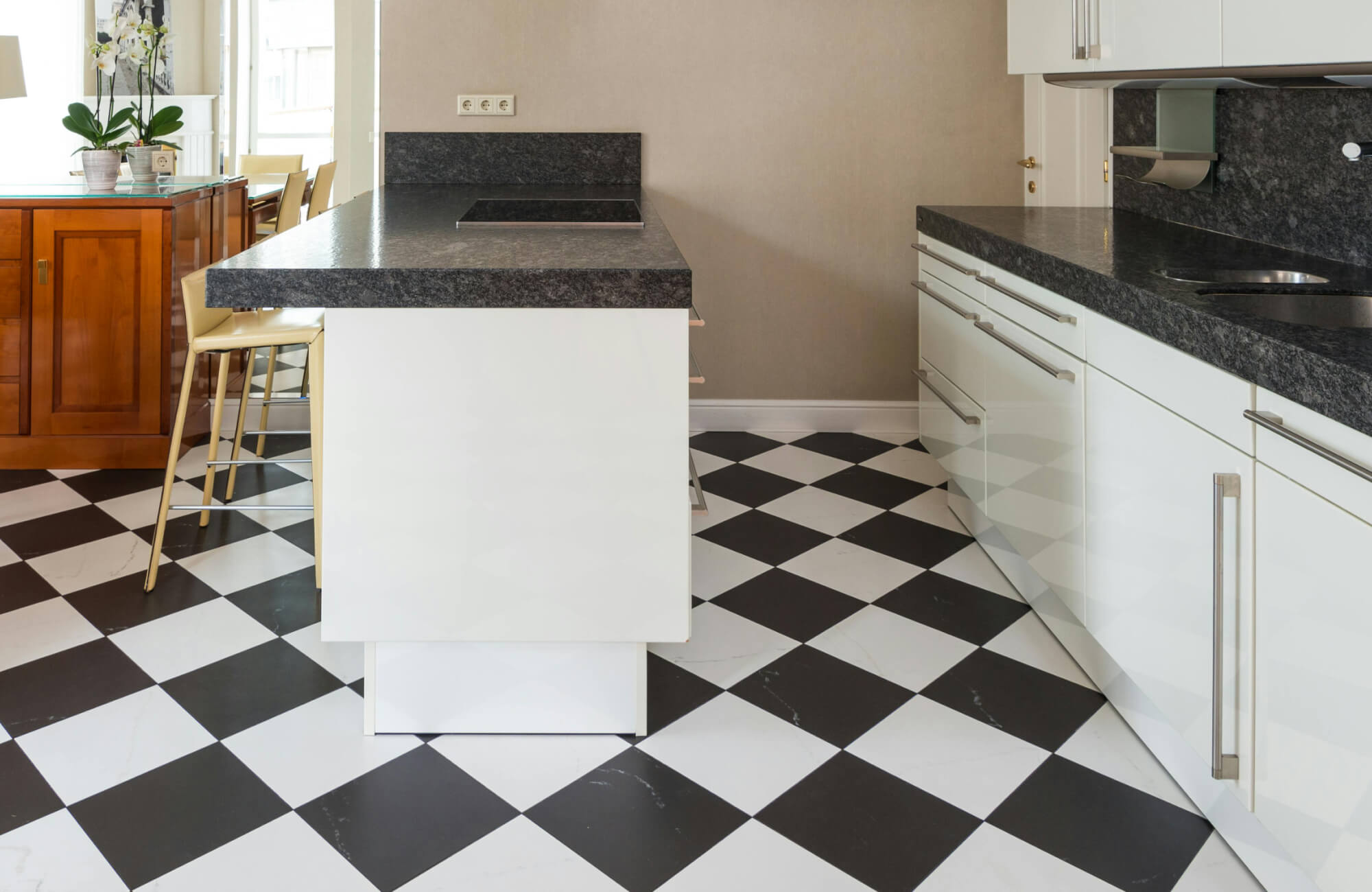 Classic black and white checkerboard tile flooring adds timeless elegance to this modern kitchen.