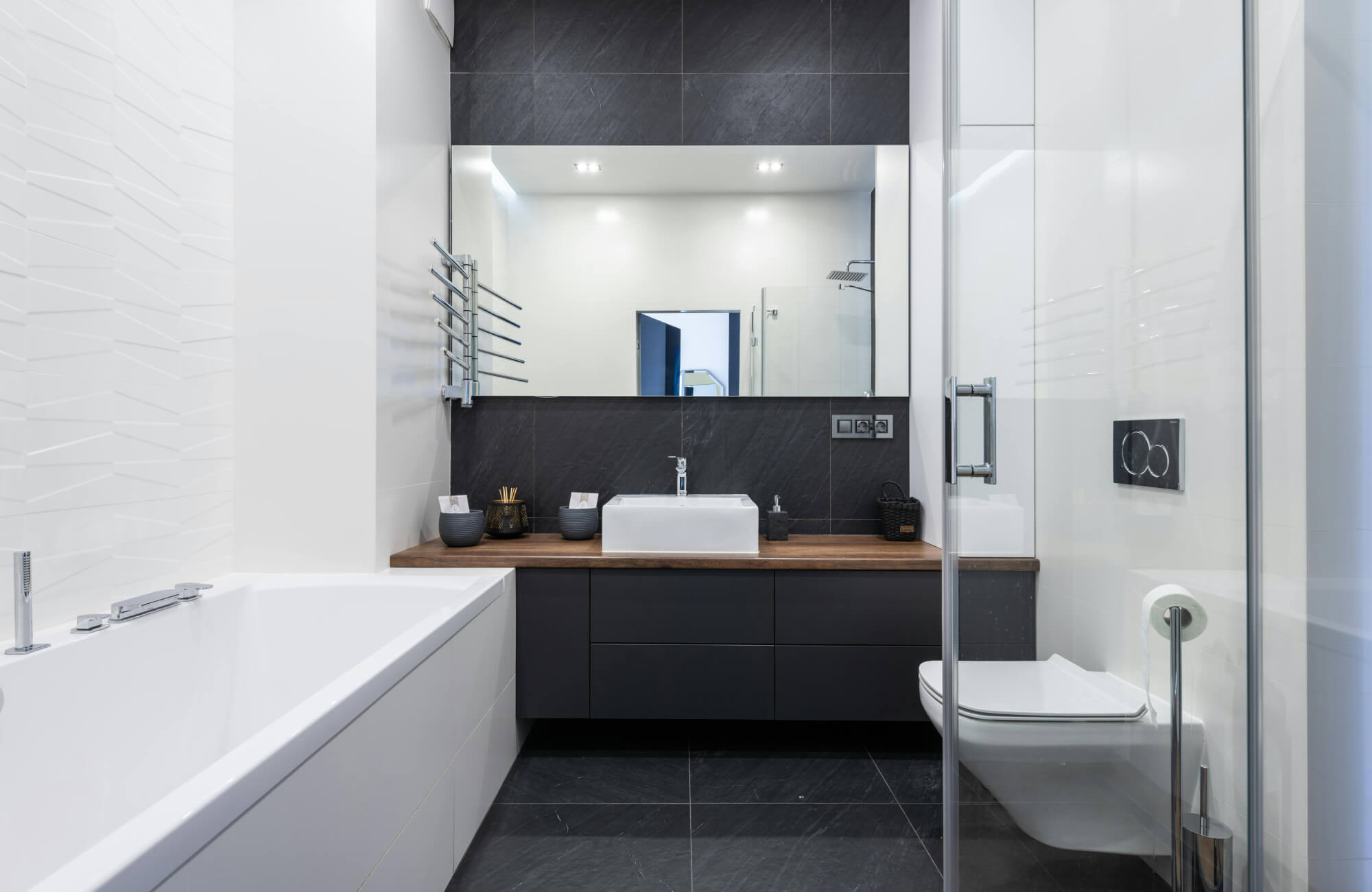 Modern bathroom with a black vanity, white sink, and large mirror, creating an open, spacious look with clean contrast.