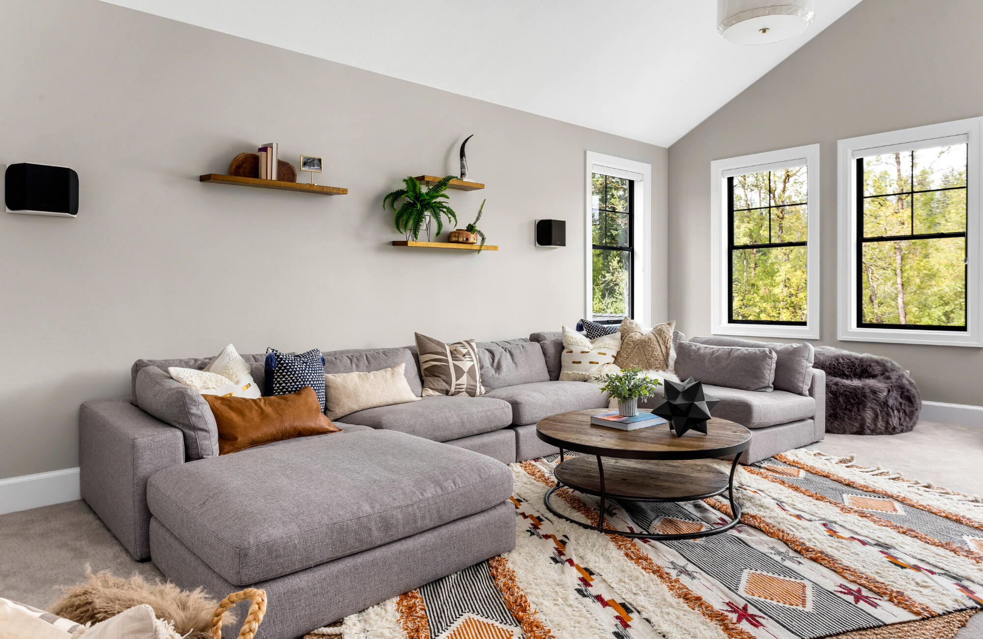 Modern living room with a gray sectional sofa, patterned throw pillows, and a bold geometric rug featuring warm orange and black accents.