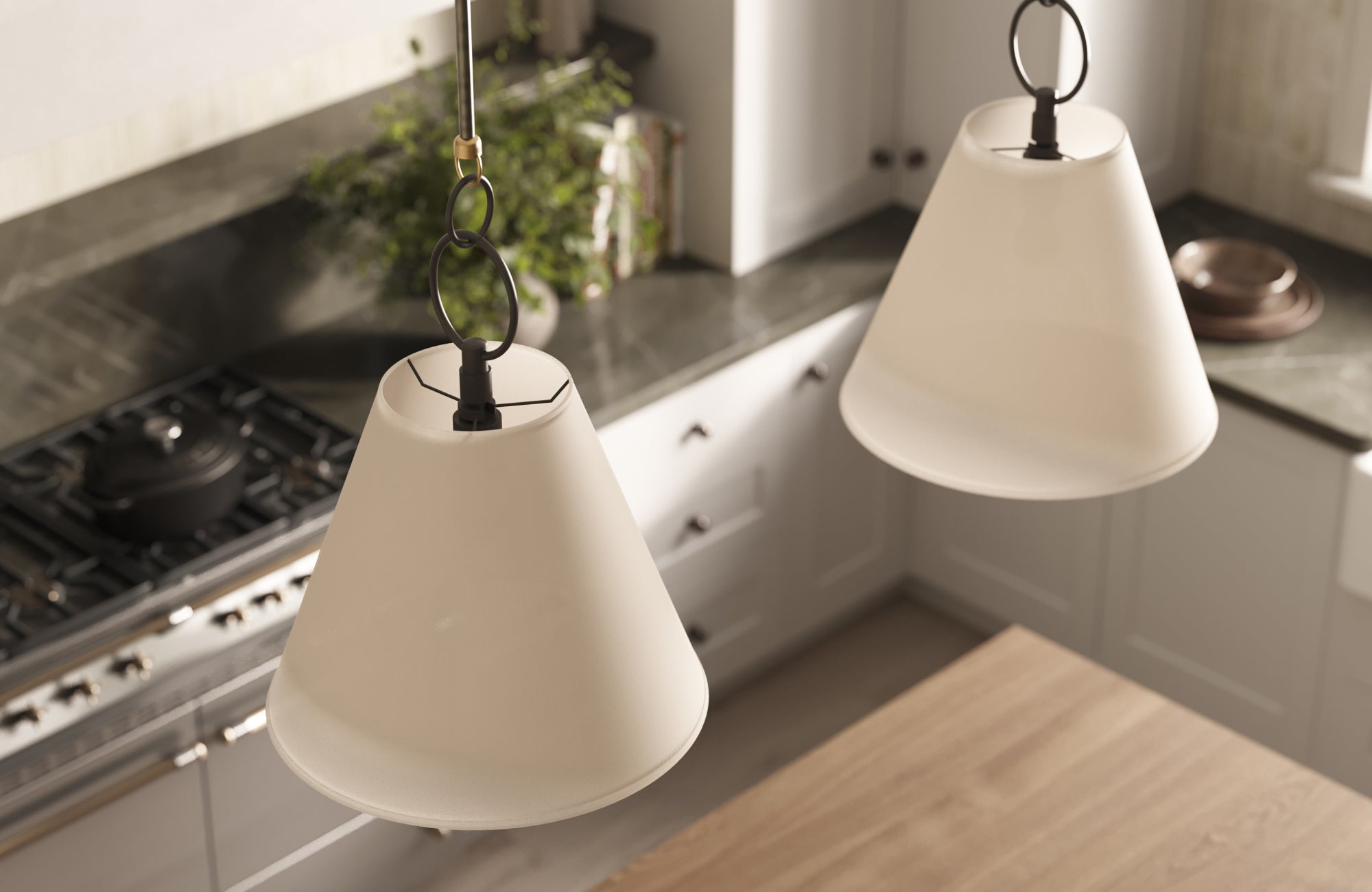 Close-up of two white pendant lights hanging above a kitchen island with a wood countertop and modern cabinetry.