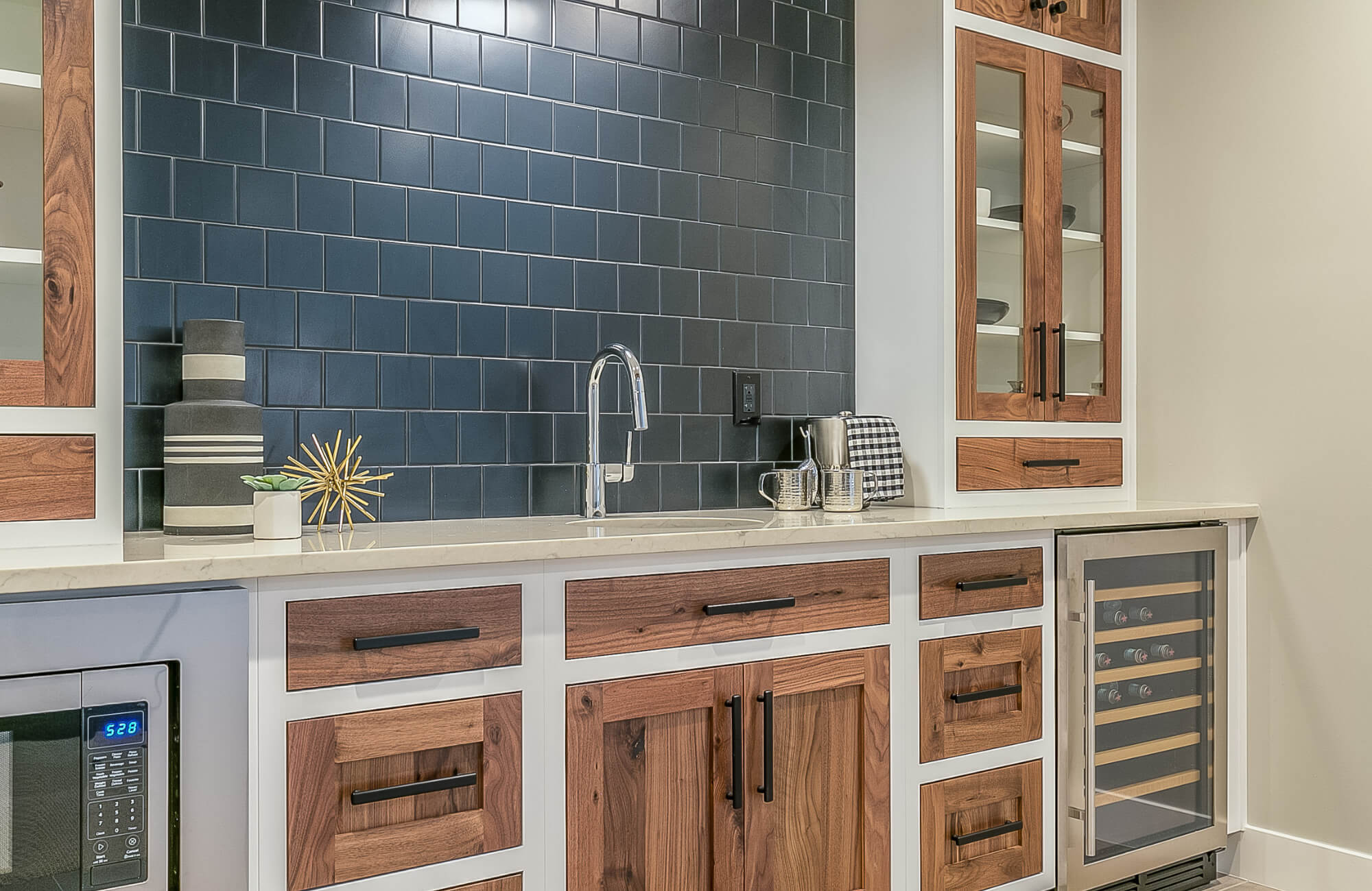 Modern kitchen with deep blue subway tile backsplash, natural wood cabinetry, quartz countertops, and stainless steel fixtures.