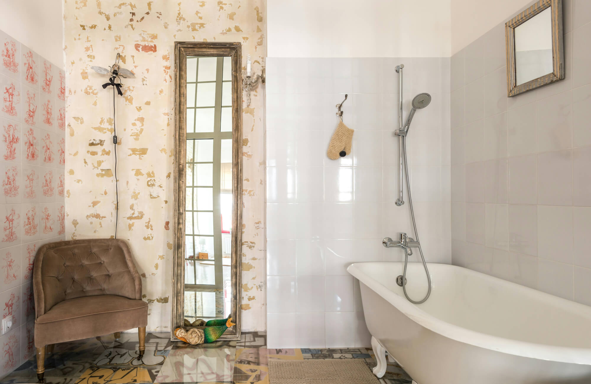 Eclectic bathroom with glossy white wall tiles, vintage clawfoot tub, and a rustic full length mirror leaning against distressed plaster.