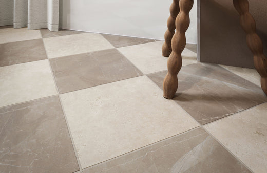 Elegant checkerboard tile flooring with large square tiles in soft beige and muted taupe tones, creating a sophisticated, natural stone look that pairs beautifully with wood accents.