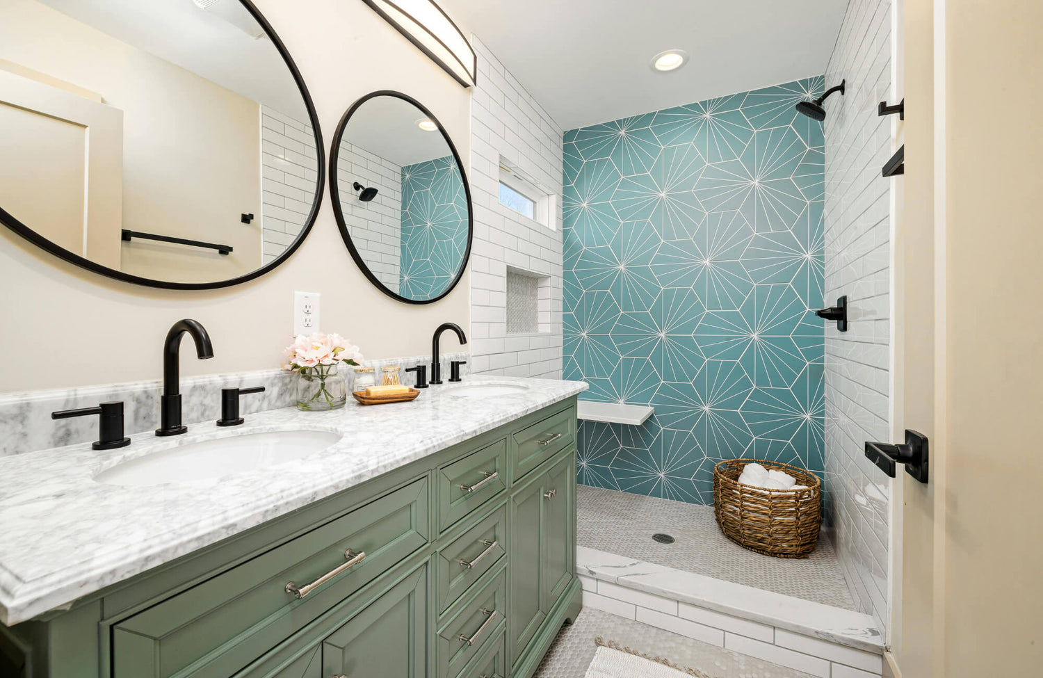 Bathroom with a green double-sink vanity, marble countertop, round mirrors, and a walk-in shower featuring teal geometric tile.