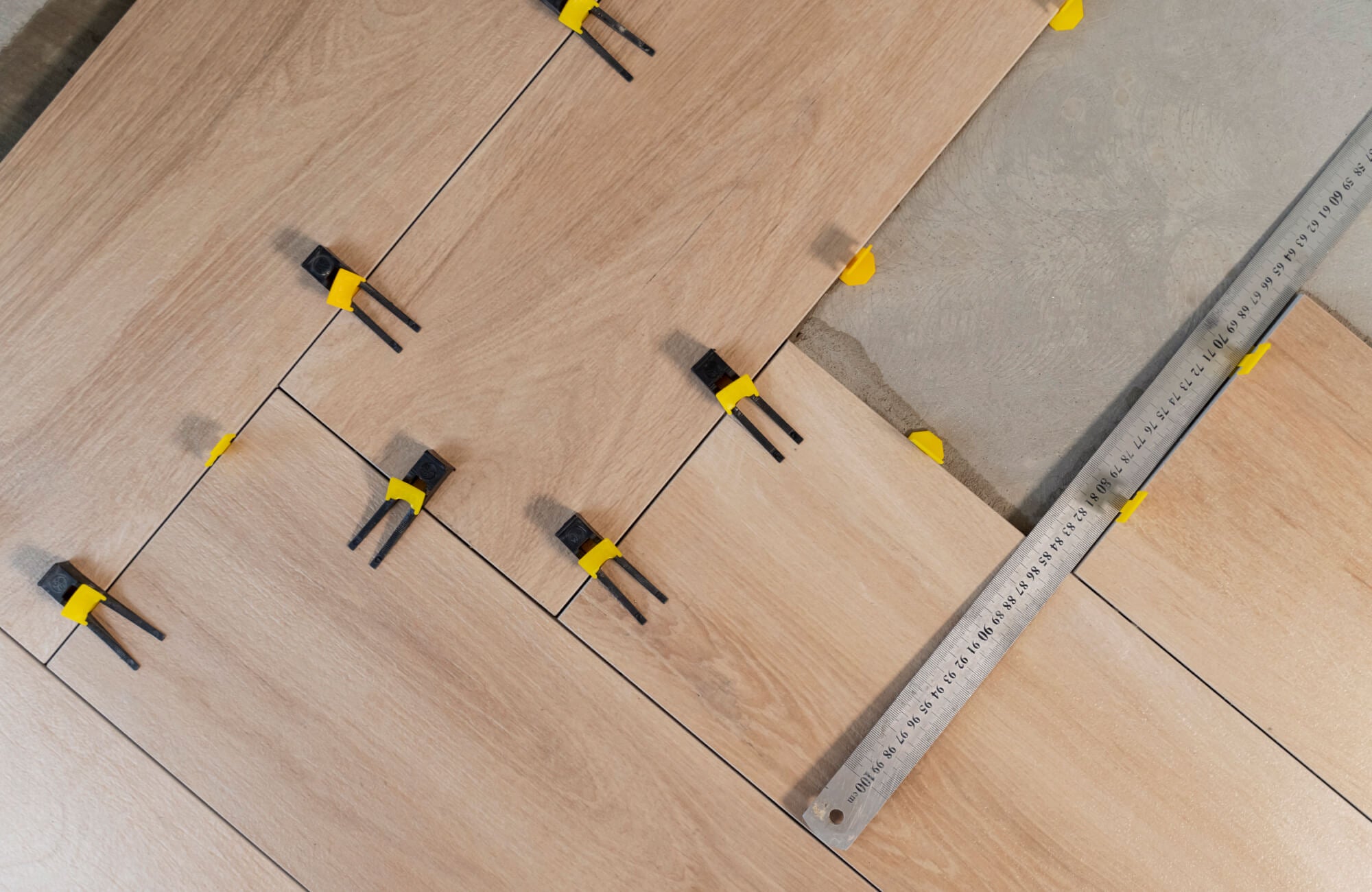 Wood look porcelain tiles being installed with a leveling system, ensuring precise alignment and a seamless finish for a natural yet durable floor.