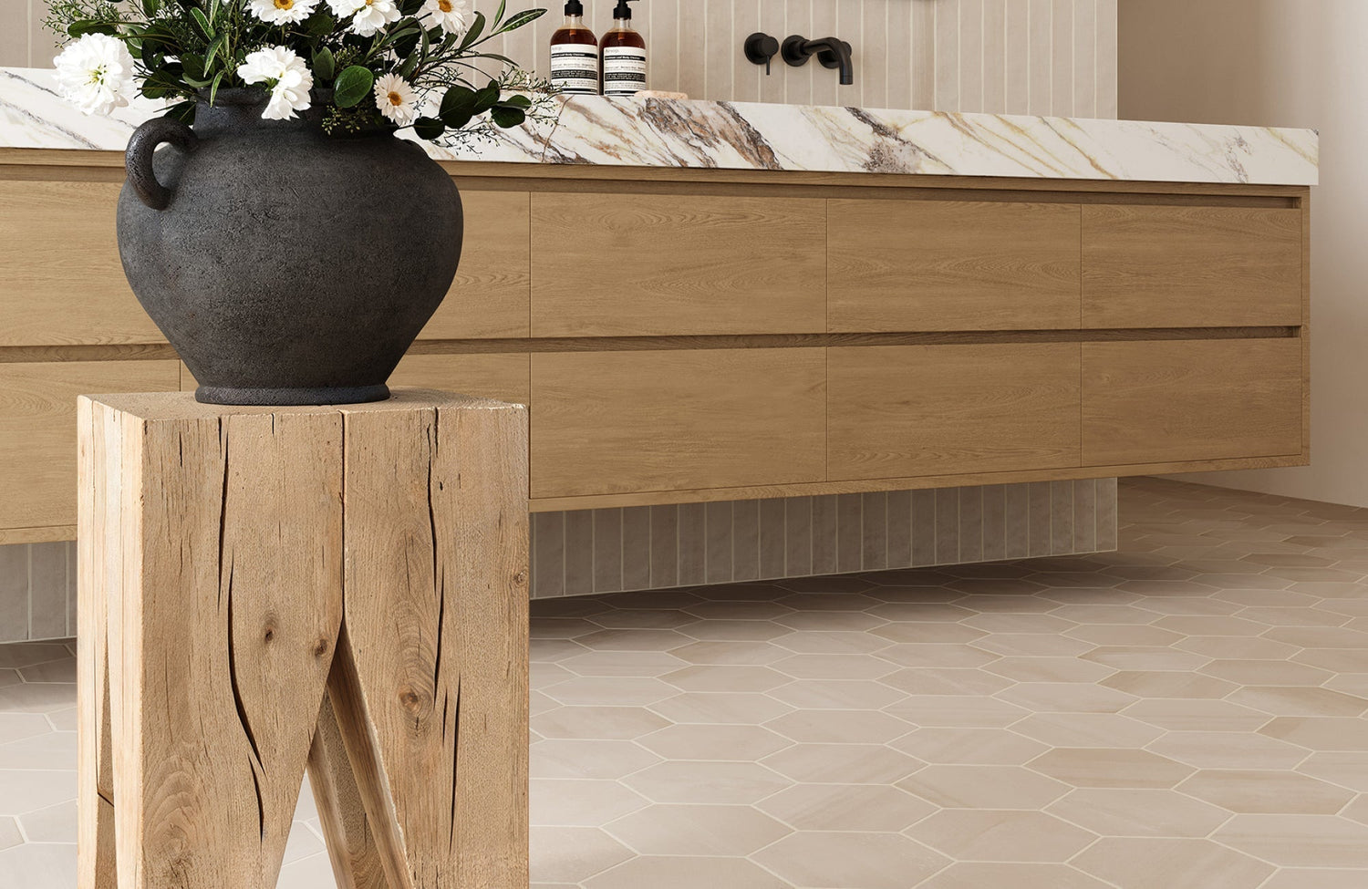 Beige hex tile bathroom floor with subtle shading, paired with a natural wood vanity and marble countertop.