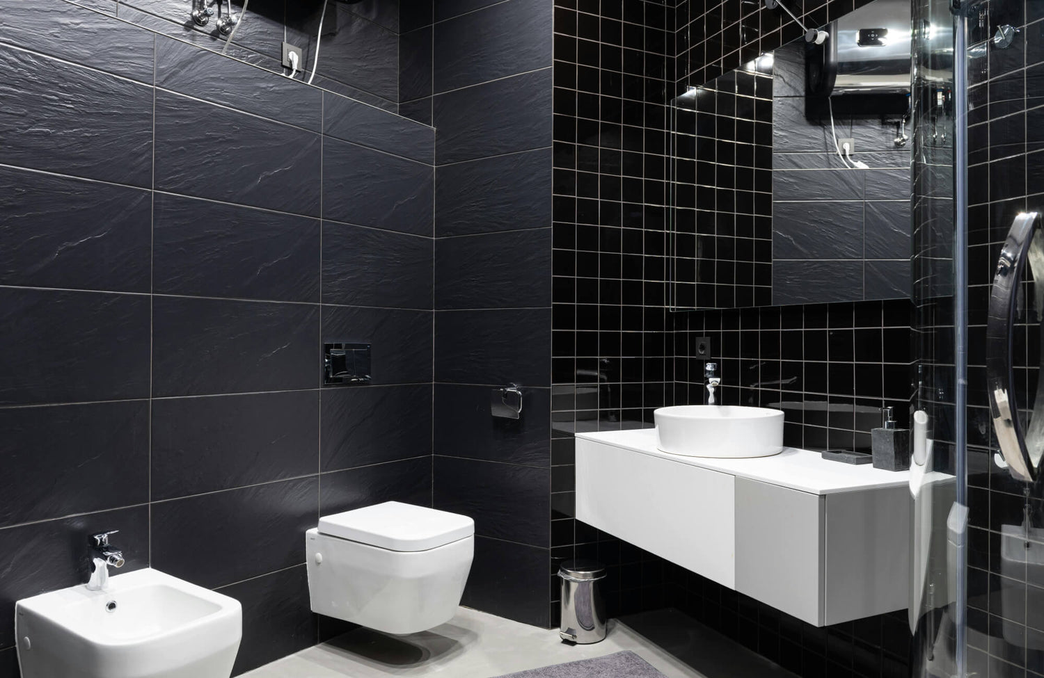 Modern bathroom with large-format black wall tiles and matte black fixtures, showcasing tile texture and contrast.