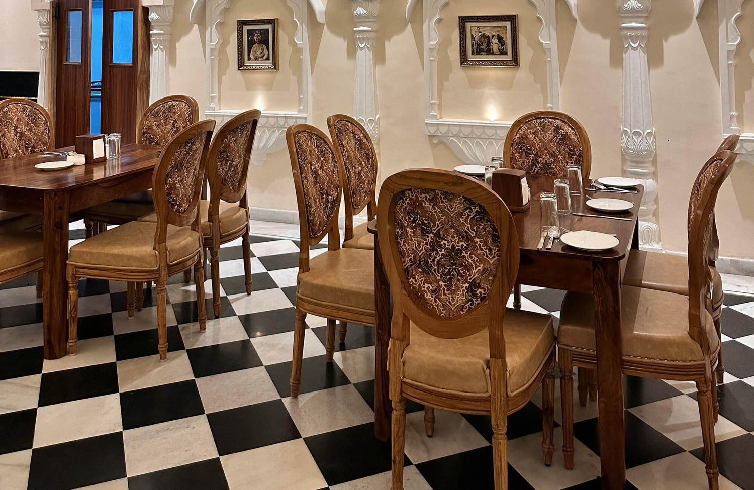 Elegant dining area with carved wooden chairs, set on a classic black and white checkerboard tile floor.