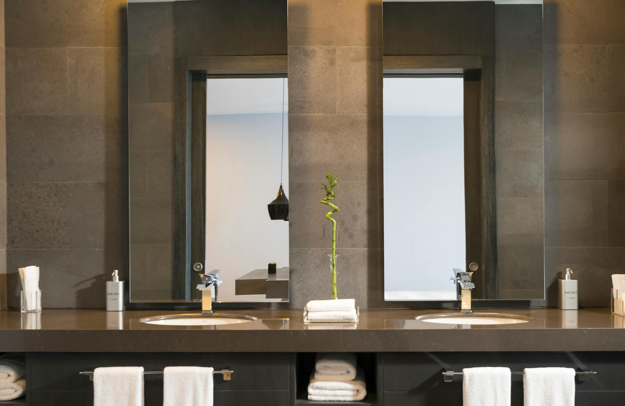 Contemporary bathroom with sleek stone finishes and a large bathroom mirror above dual sinks, creating balance and a spacious feel.