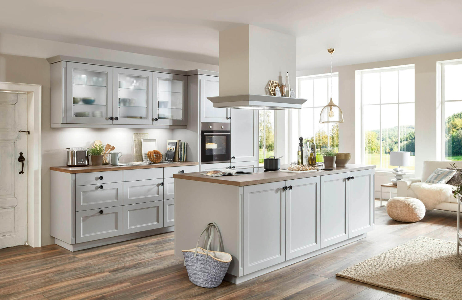 Modern farmhouse-style kitchen with light gray cabinetry, wood-look tile flooring, and a cozy open-concept design with natural light.