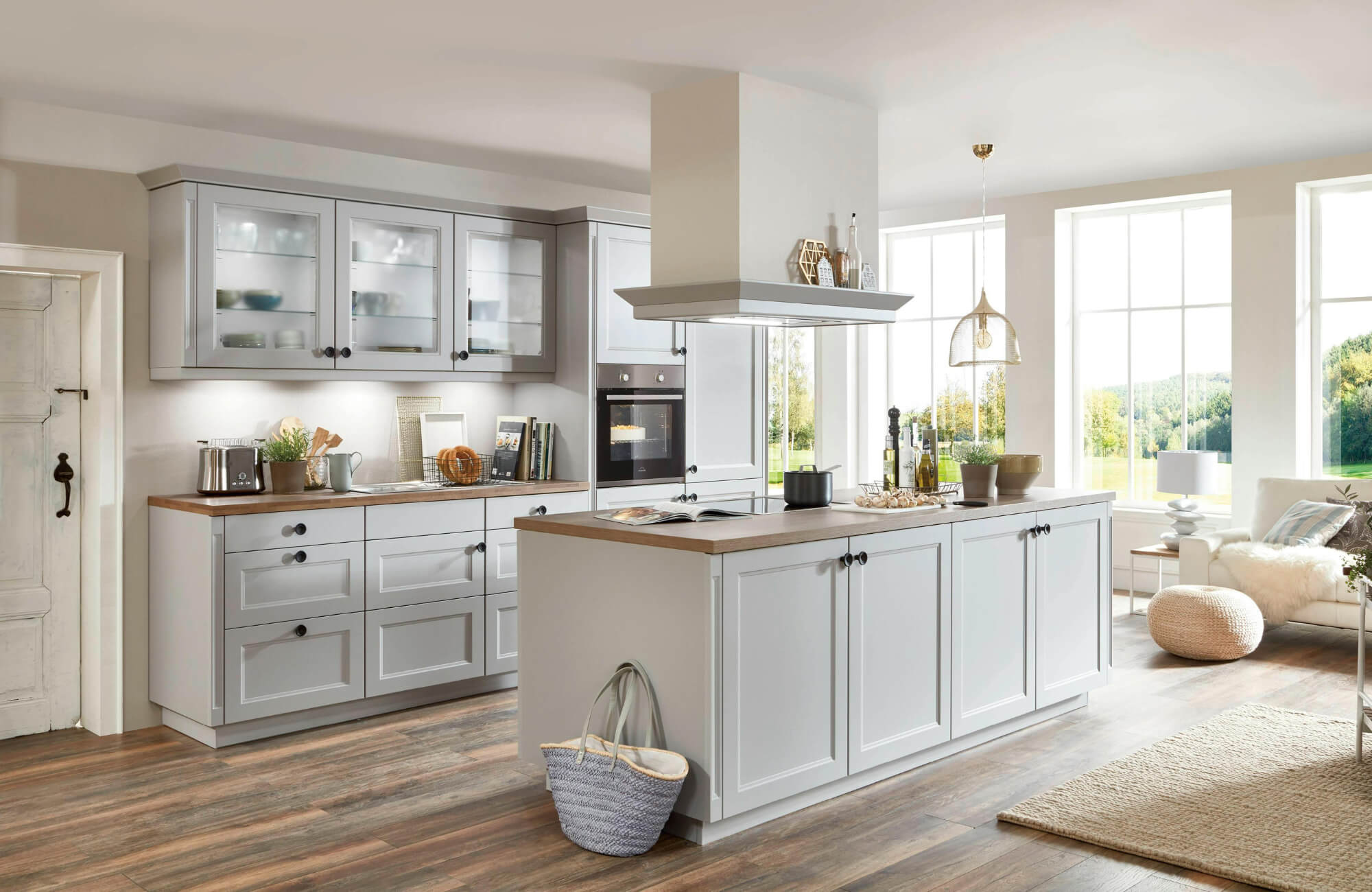 Modern farmhouse-style kitchen with light gray cabinetry, wood-look tile flooring, and a cozy open-concept design with natural light.