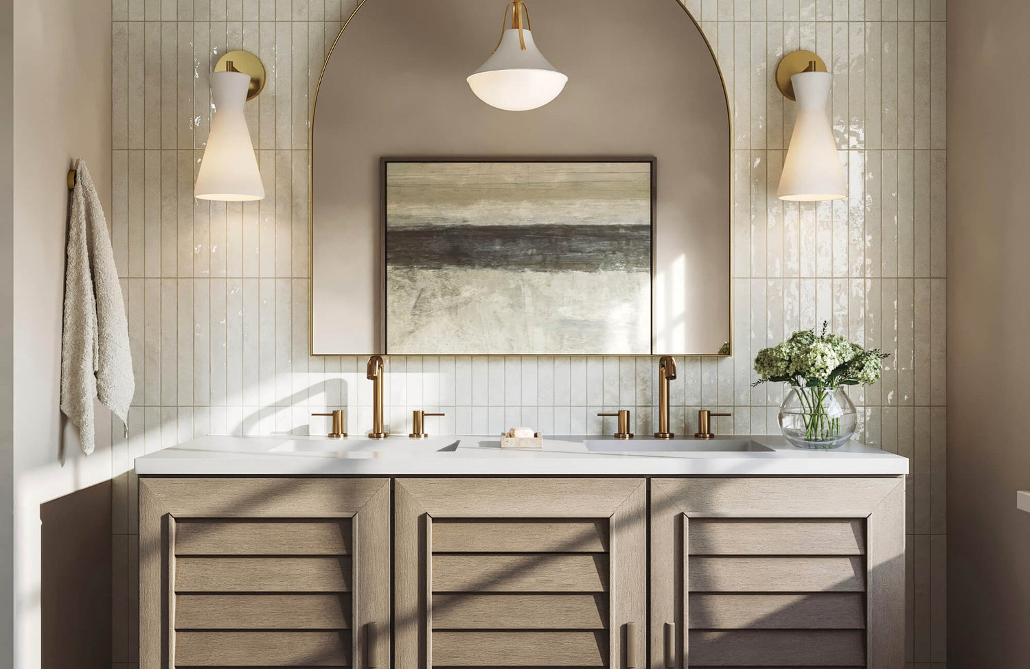 Modern bathroom featuring a brass arch mirror, warm sconces, dual sinks, and wood cabinetry with soft neutral tile walls.
