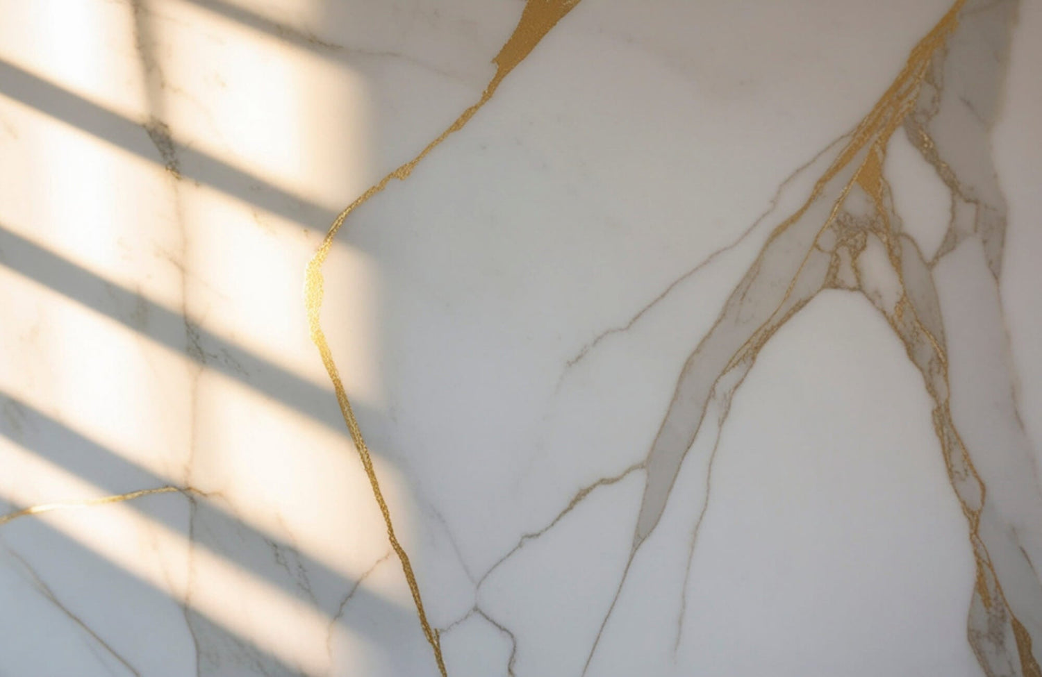 Sunlight casting shadows across white marble with gold veining, highlighting natural stone texture and surface appearance in bright light.