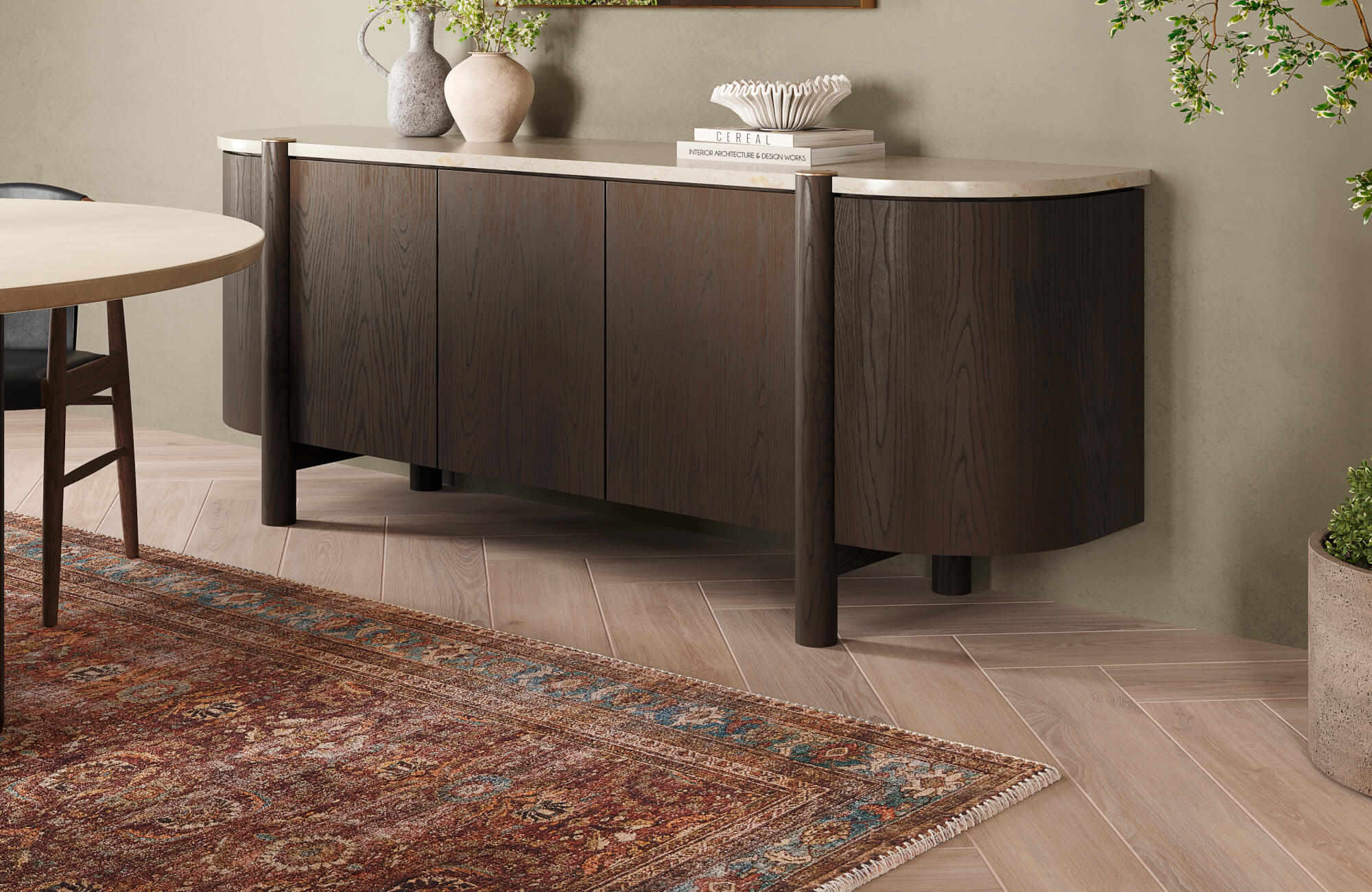 Elegant dining space featuring a 9x6 rug with intricate patterns in warm rust and blue tones, complementing the dark wood sideboard and light herringbone flooring for a refined, balanced look.