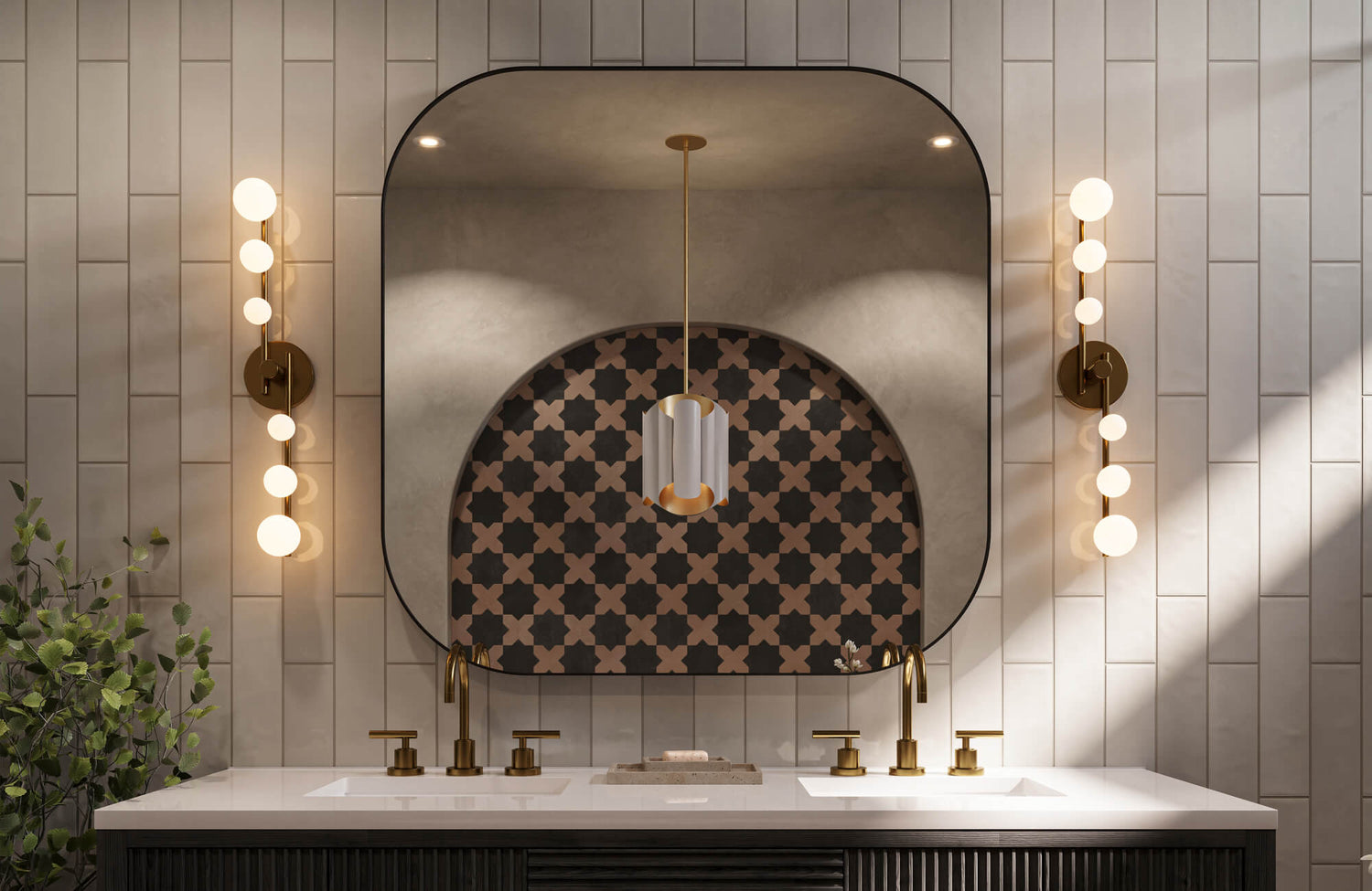 A stylish bathroom with brass faucets, matching globe sconces, and an arched mirror backed by bold patterned tile, illuminated with soft, even vanity lighting.