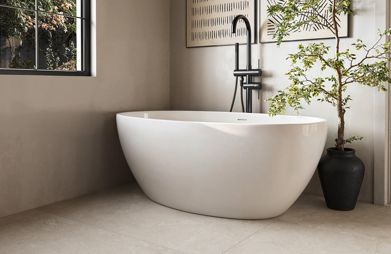 Light beige stone-look flooring paired with a freestanding tub, matte black fixtures, and a potted plant creates a warm, spa-like setting that makes a small bathroom feel more open and inviting.