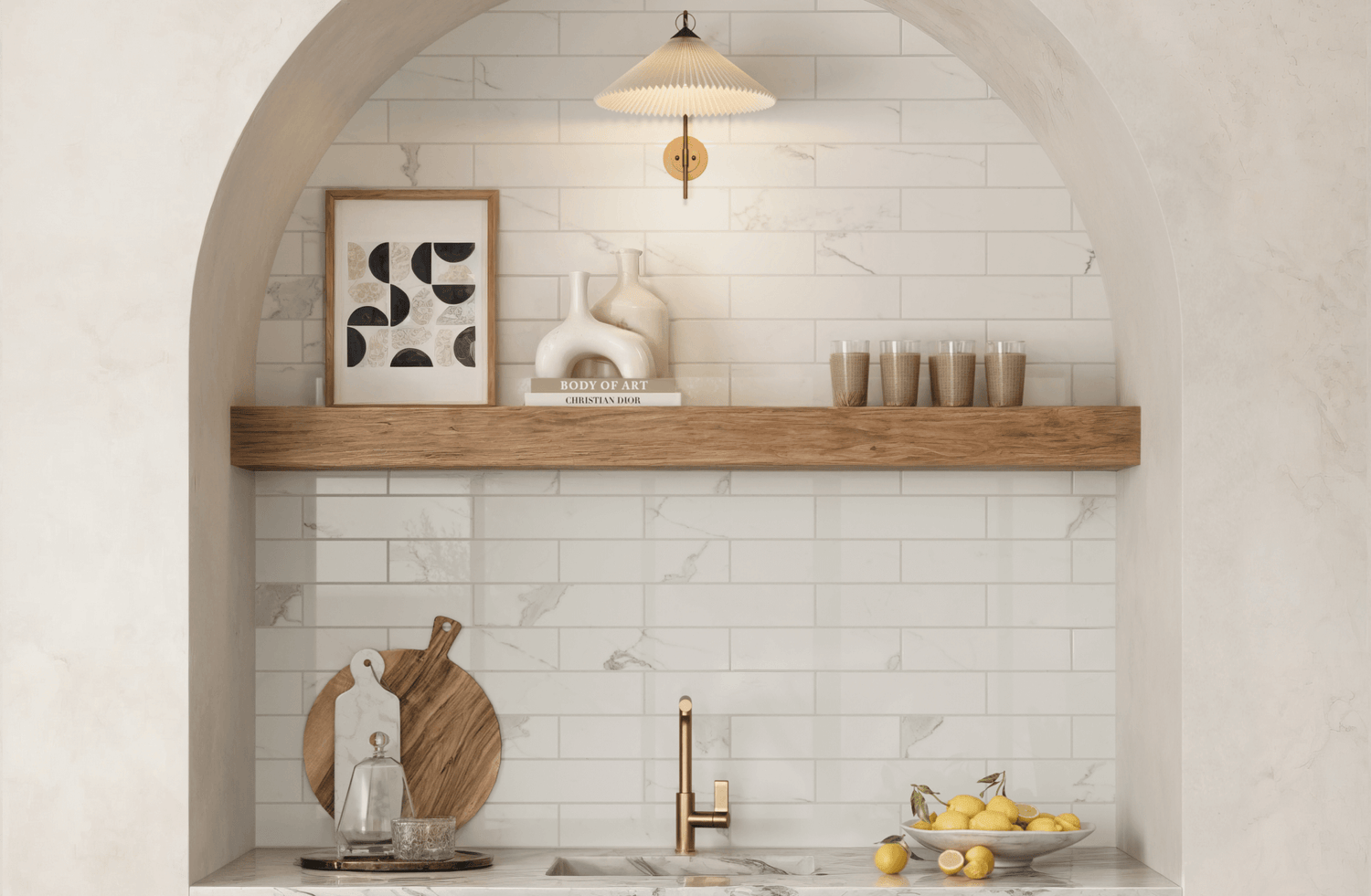 White subway tiles line the arched kitchen nook, providing a clean, timeless backdrop that contrasts with a natural wood shelf and brass faucet.