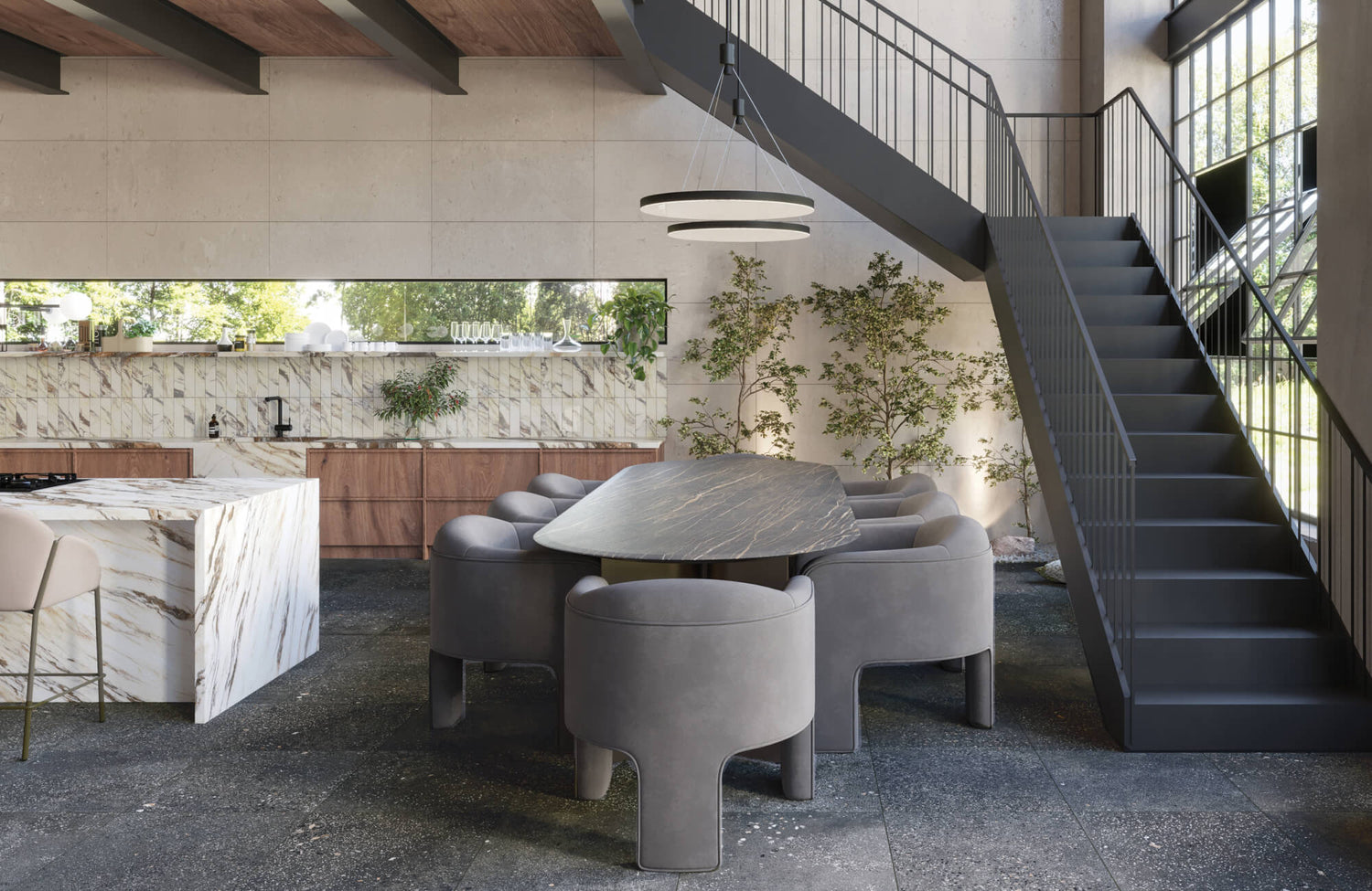 Sleek open-plan kitchen featuring cement look stone floor tiles, veined marble surfaces, and plush grey dining chairs in a modern setting.