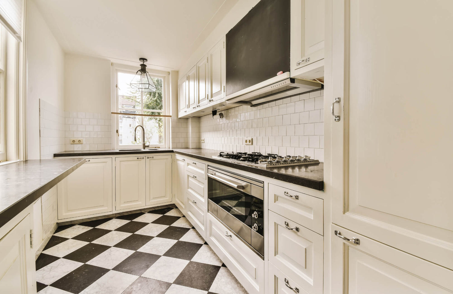 Classic black and white checkerboard tiles enhance this bright kitchen, creating depth and contrast against the crisp white cabinetry.