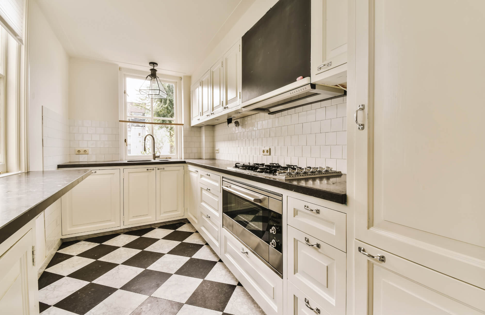 Classic black and white checkerboard tiles enhance this bright kitchen, creating depth and contrast against the crisp white cabinetry.