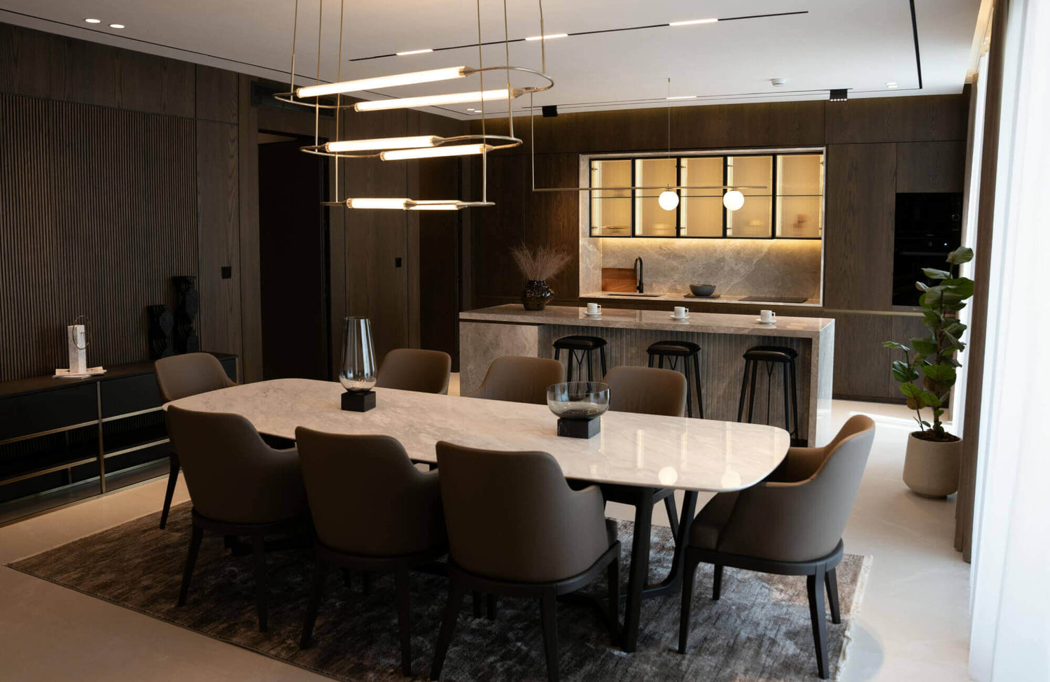 Modern dining room with a sleek rectangular marble-top table surrounded by upholstered chairs and pendant lighting.
