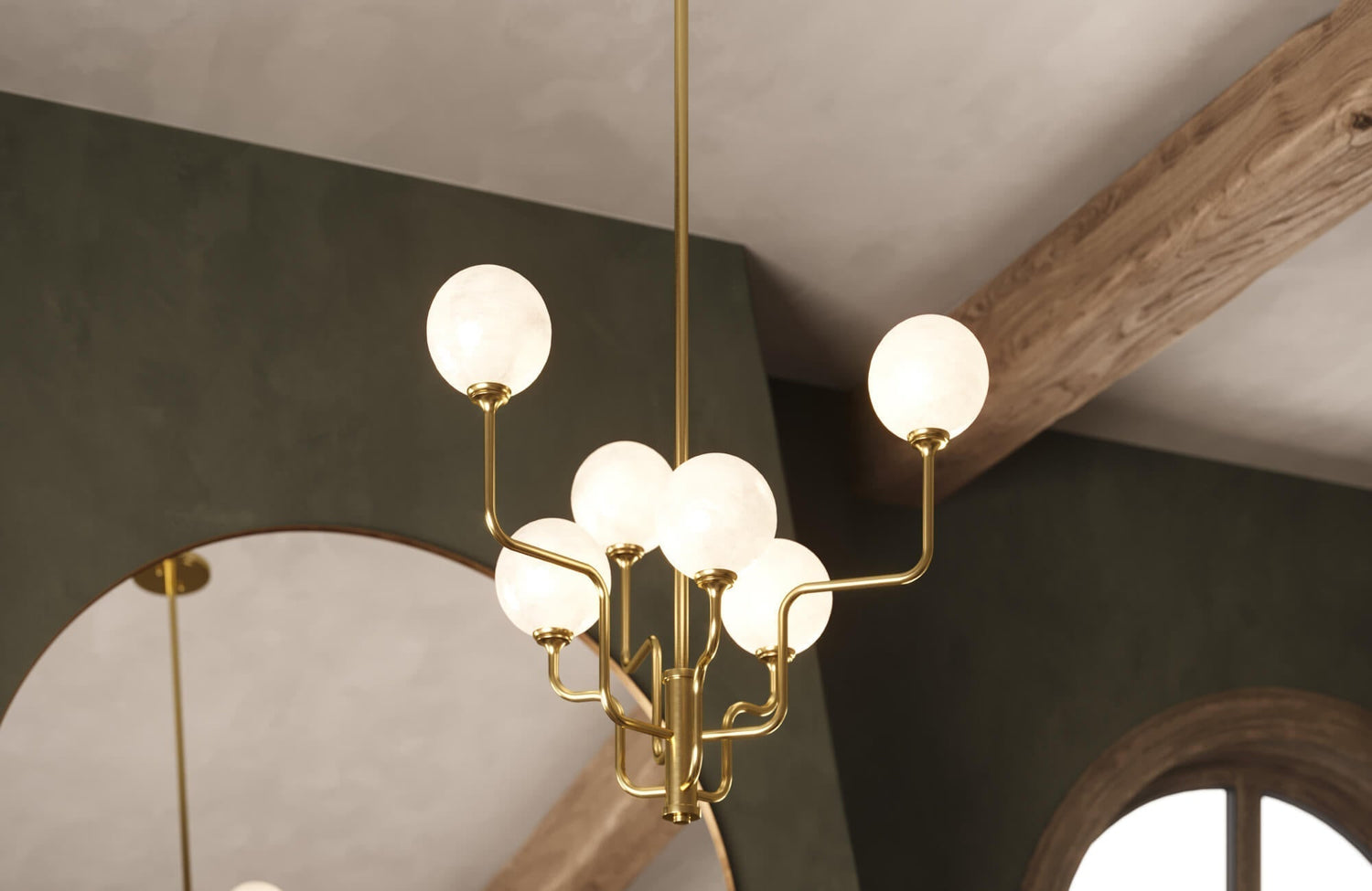 Elegant gold chandelier with round frosted bulbs, reflecting softly against a dark green accent wall and arched mirror.