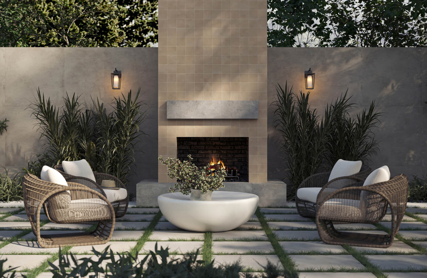 Elegant outdoor patio with woven lounge chairs, round coffee table, and built-in fireplace framed by lush greenery and warm lighting.