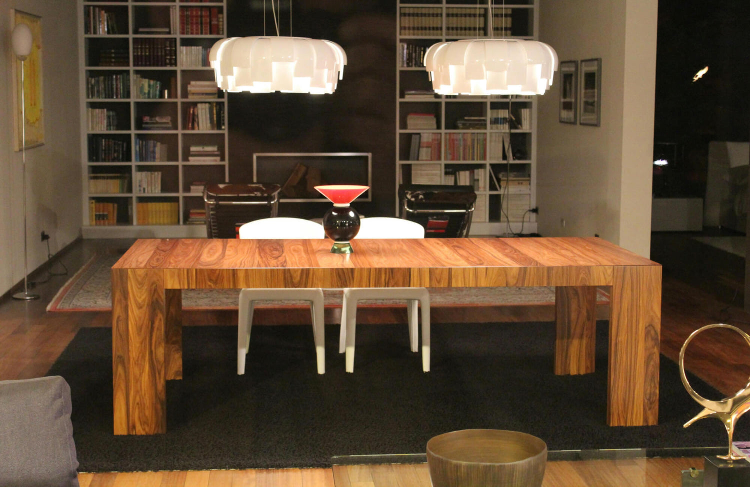 Modern dining area with a bold black rug, walnut table, white chairs, and pendant lights, styled to minimize lint and dust visibility.