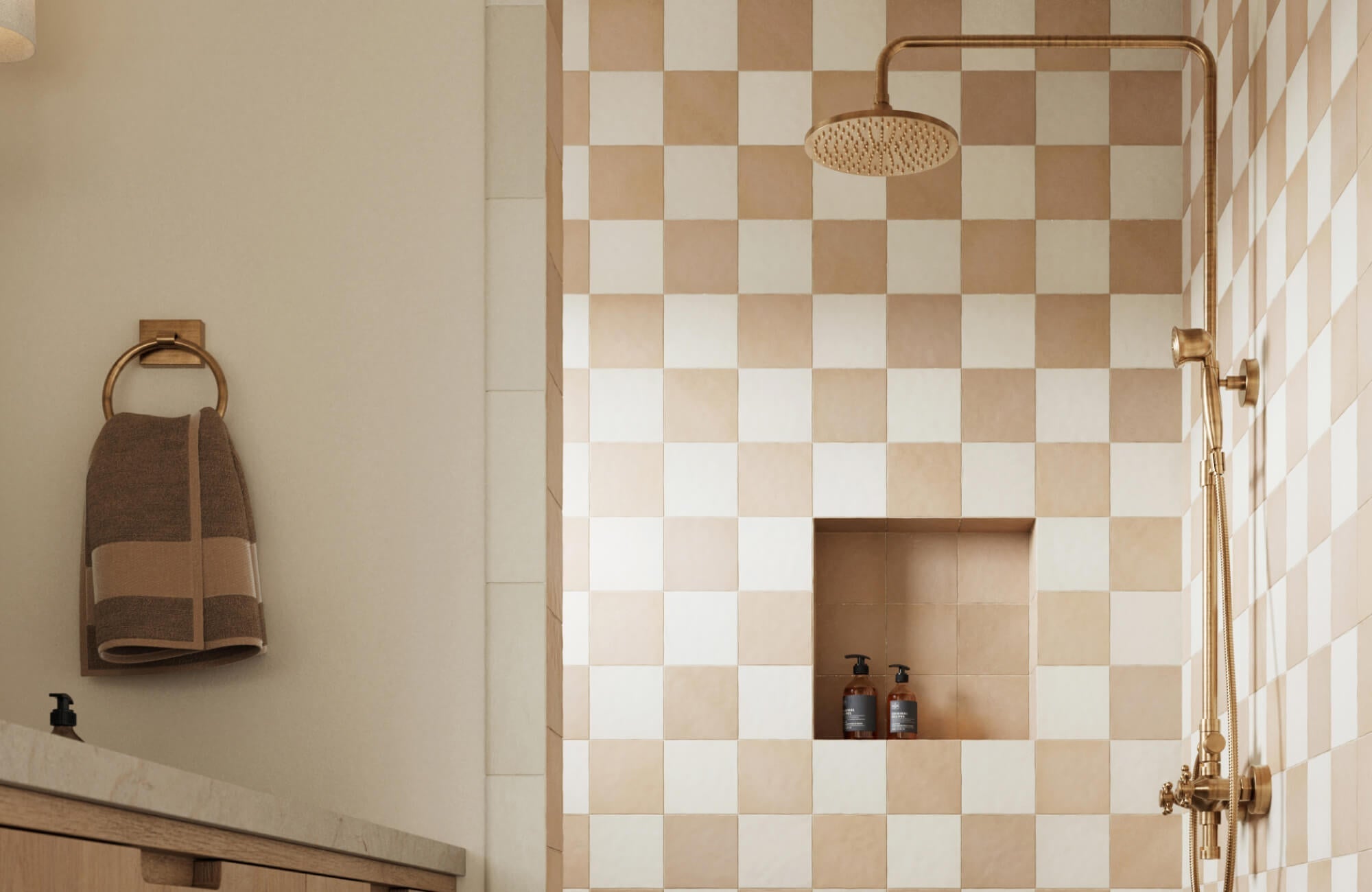 Shower with beige and white checkered tiles, brass fixtures, and a built-in niche, paired with a warm-toned vanity and towel ring for a cozy feel.