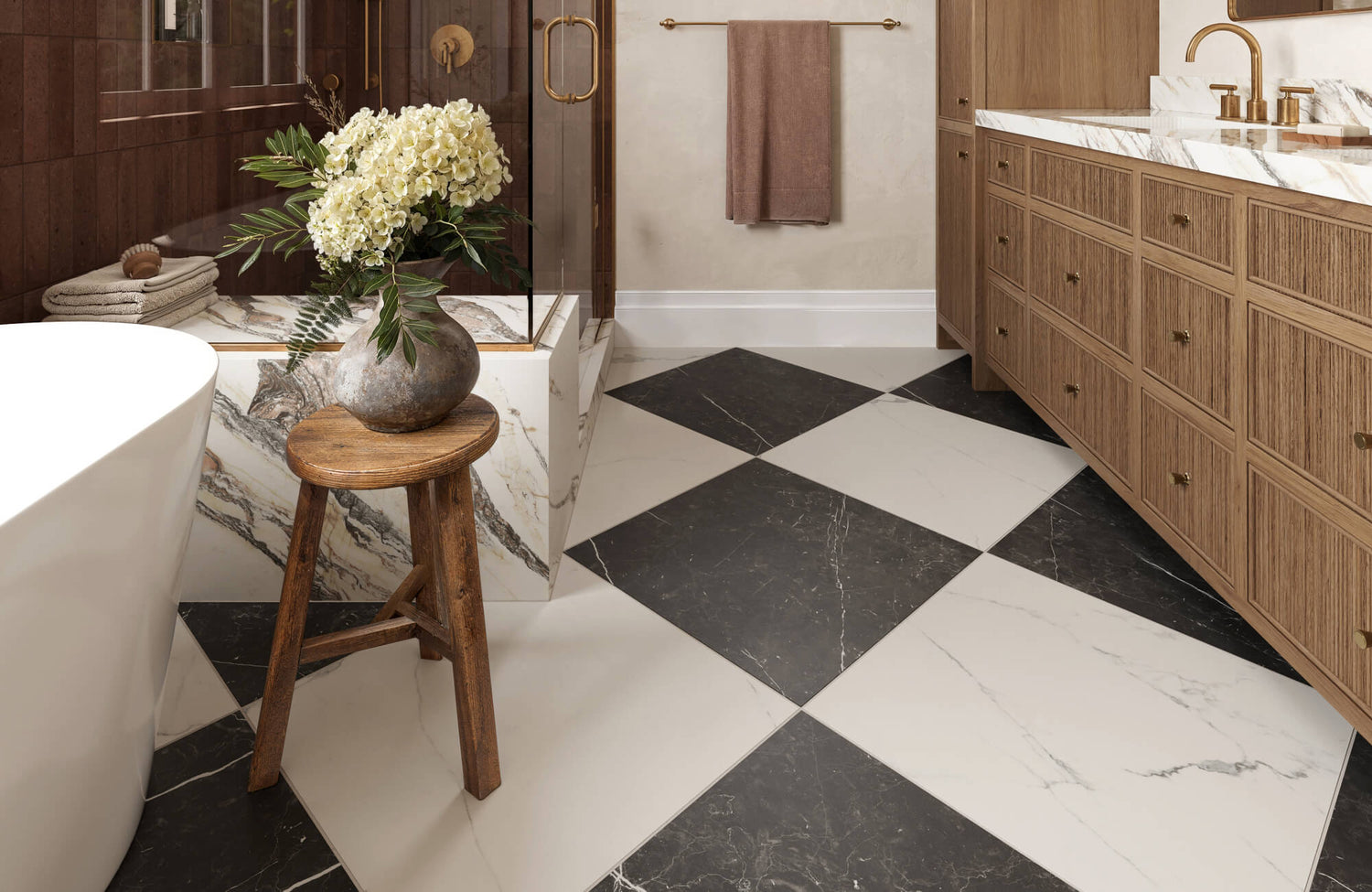 Luxurious bathroom with black and white marble look checkerboard flooring, warm wood cabinetry, and gold fixtures for a timeless, elegant look.