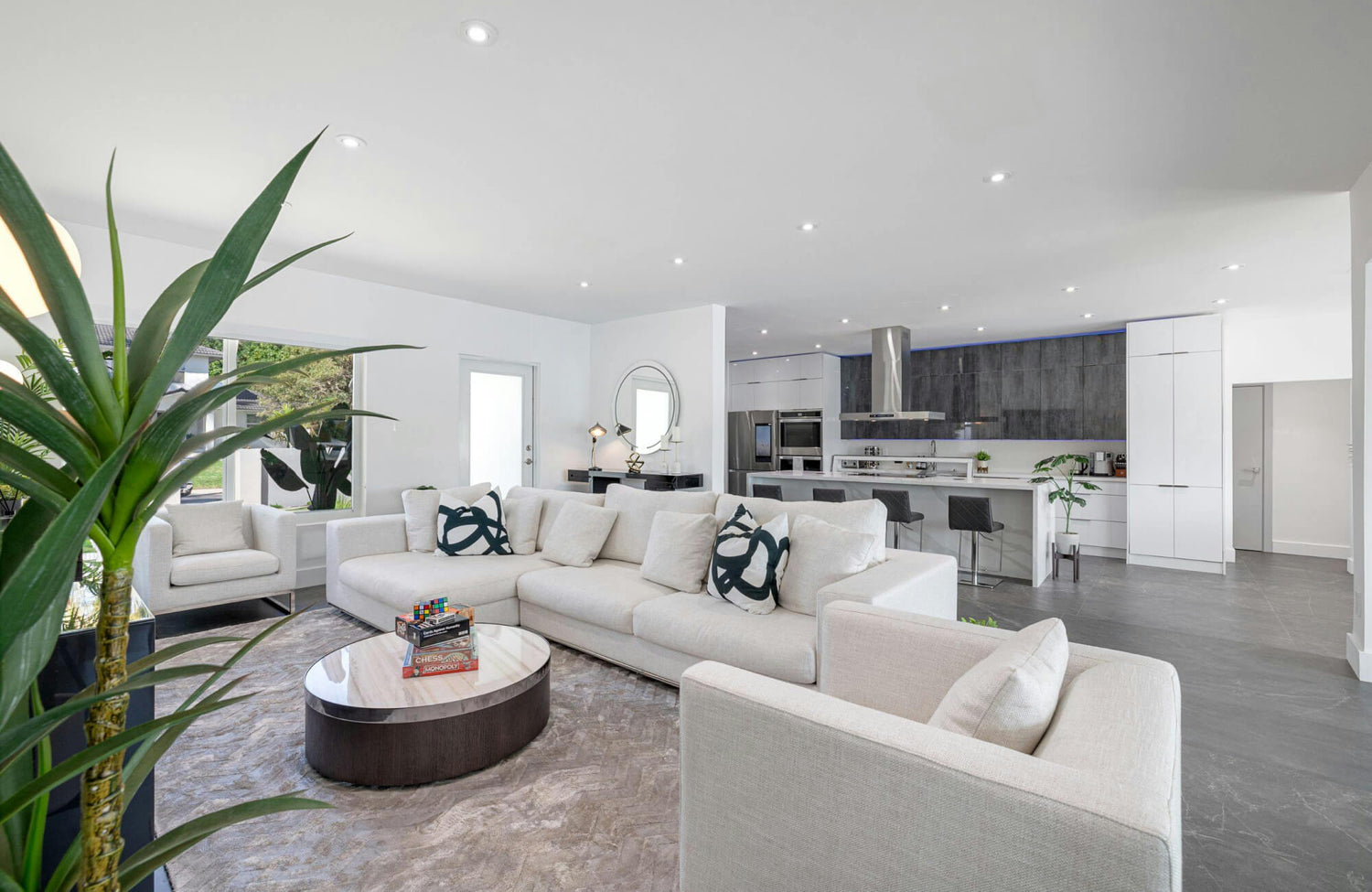 Open concept living room with decorative pillows on a light sofa, showcasing bold black patterns that add contrast to a neutral interior.