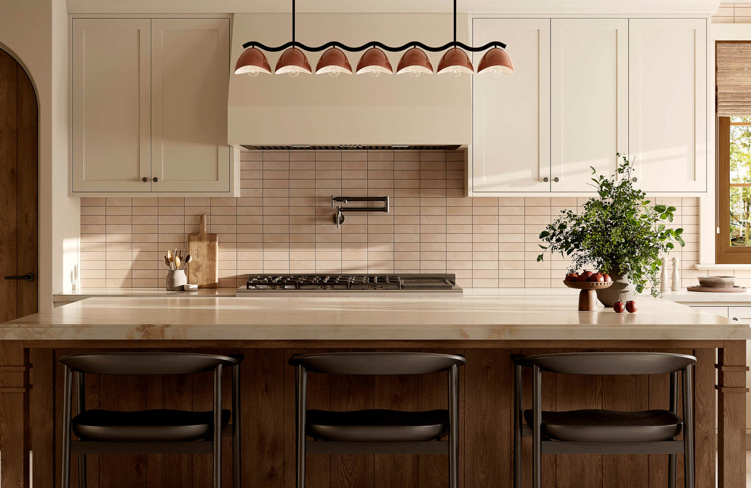 Warm contemporary kitchen with wood island seating, pale tile backsplash, cream cabinetry, sculptural linear pendant light, and greenery accent.