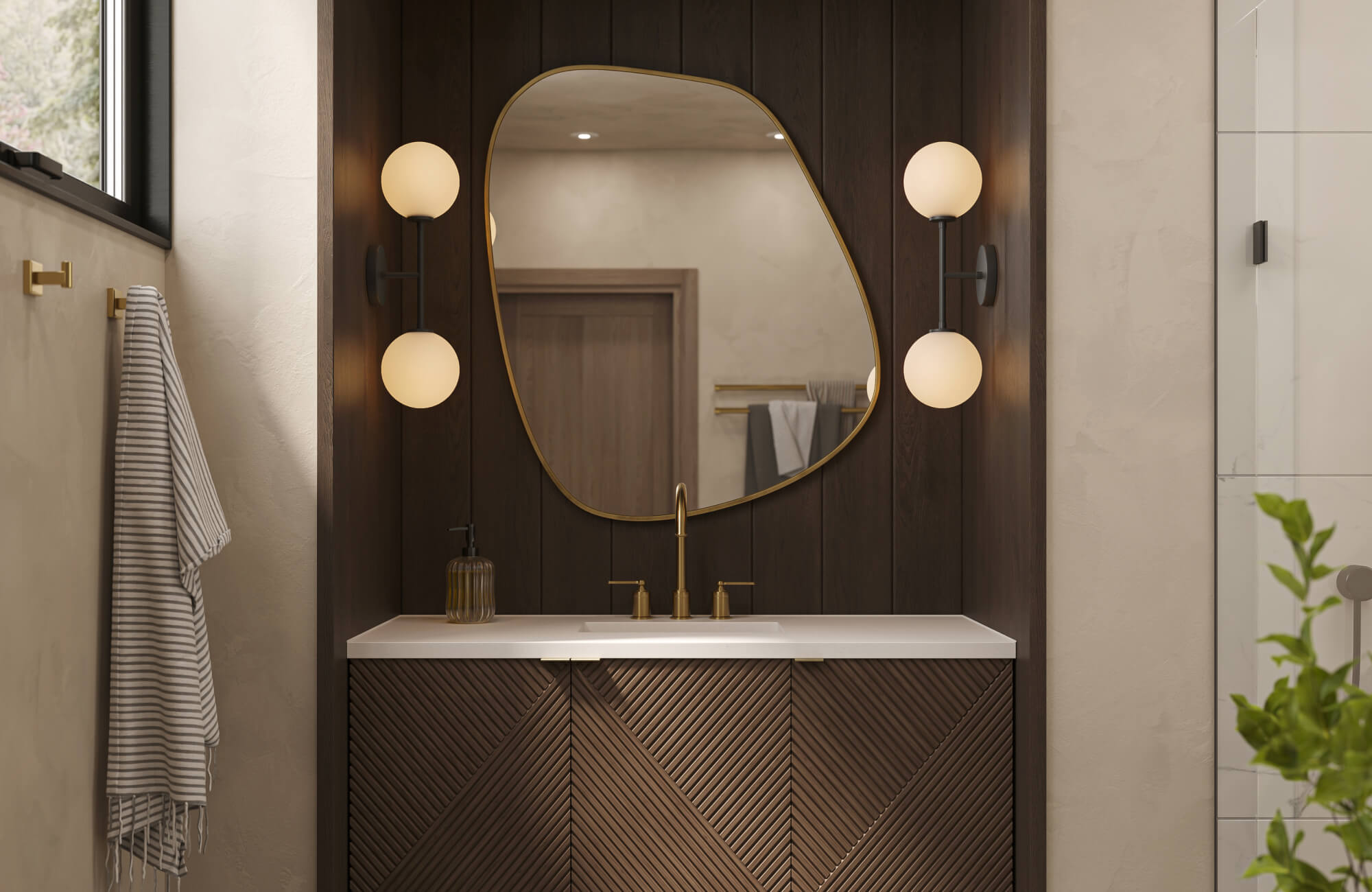 Elegant bathroom vanity with fluted wood panels, asymmetrical brass mirror, and globe sconces against rich dark wall panels.