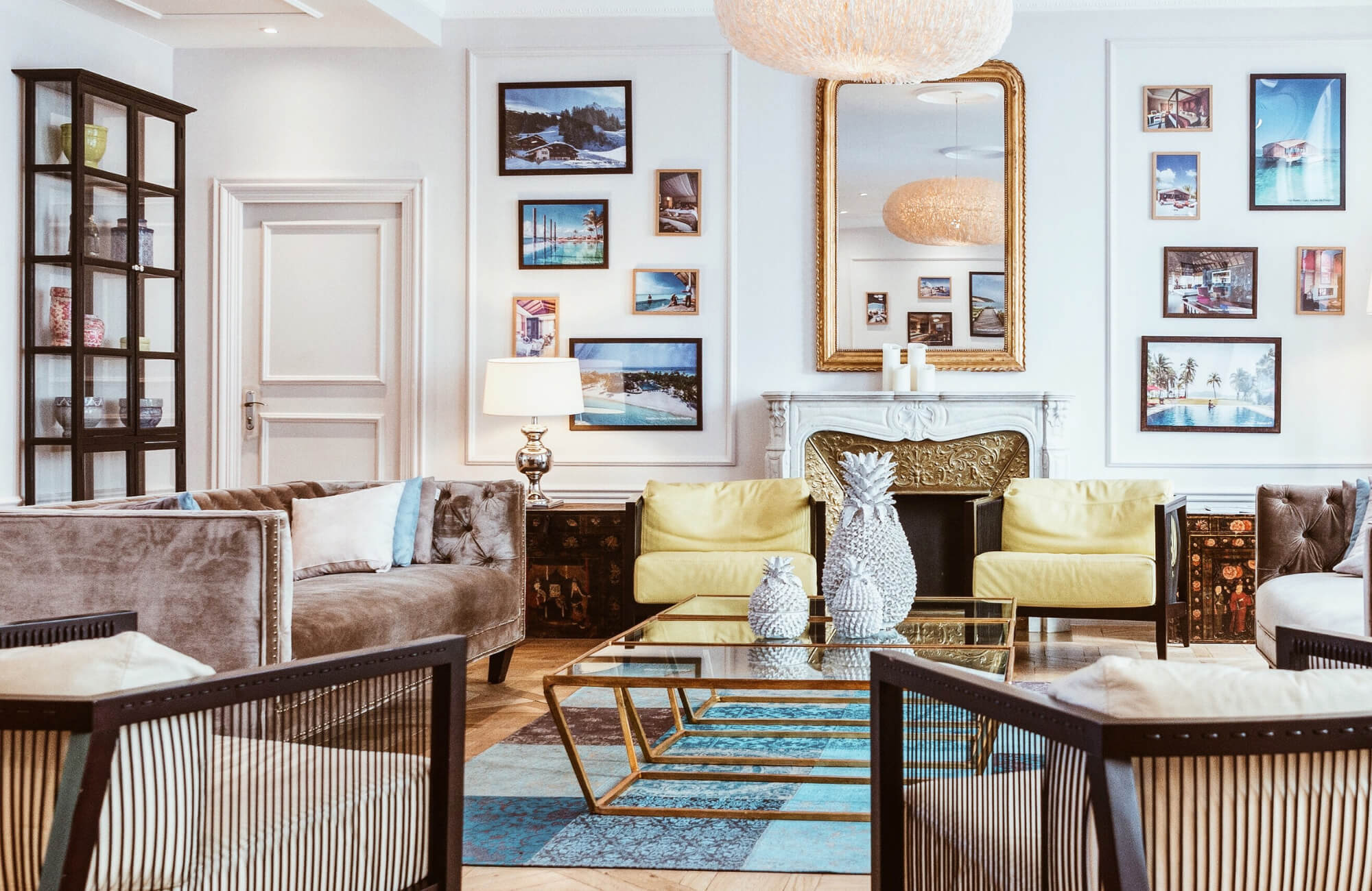 Elegant living room with a gold-framed mirror above a fireplace, modern sofas, glass coffee table, and wall art decor.